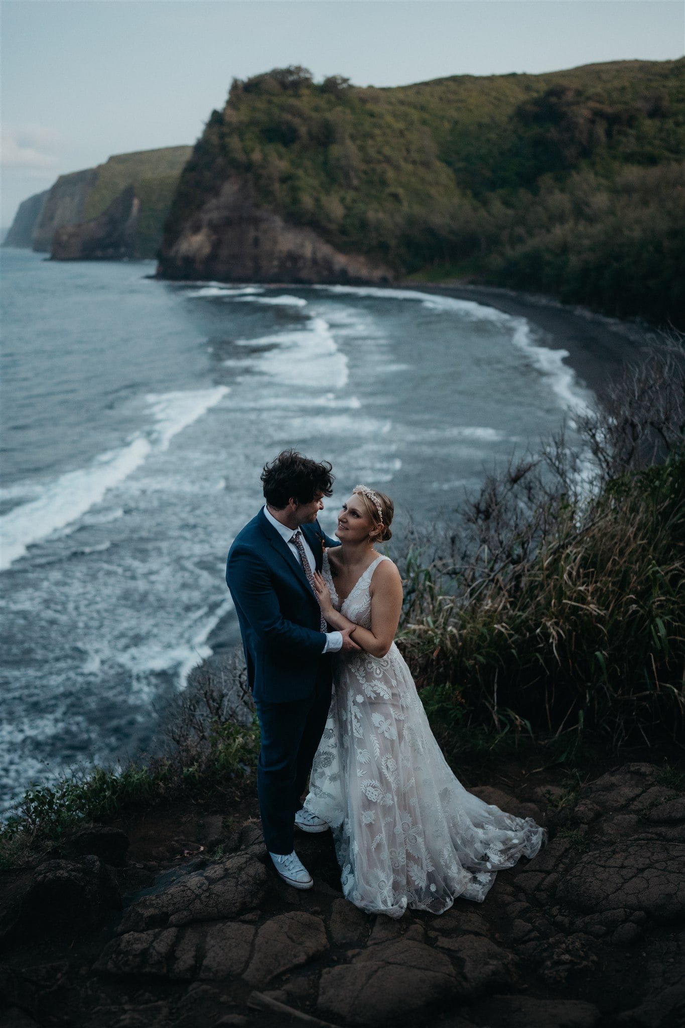 Bride and groom holding hands overlooking the ocean at their Big Island elopement