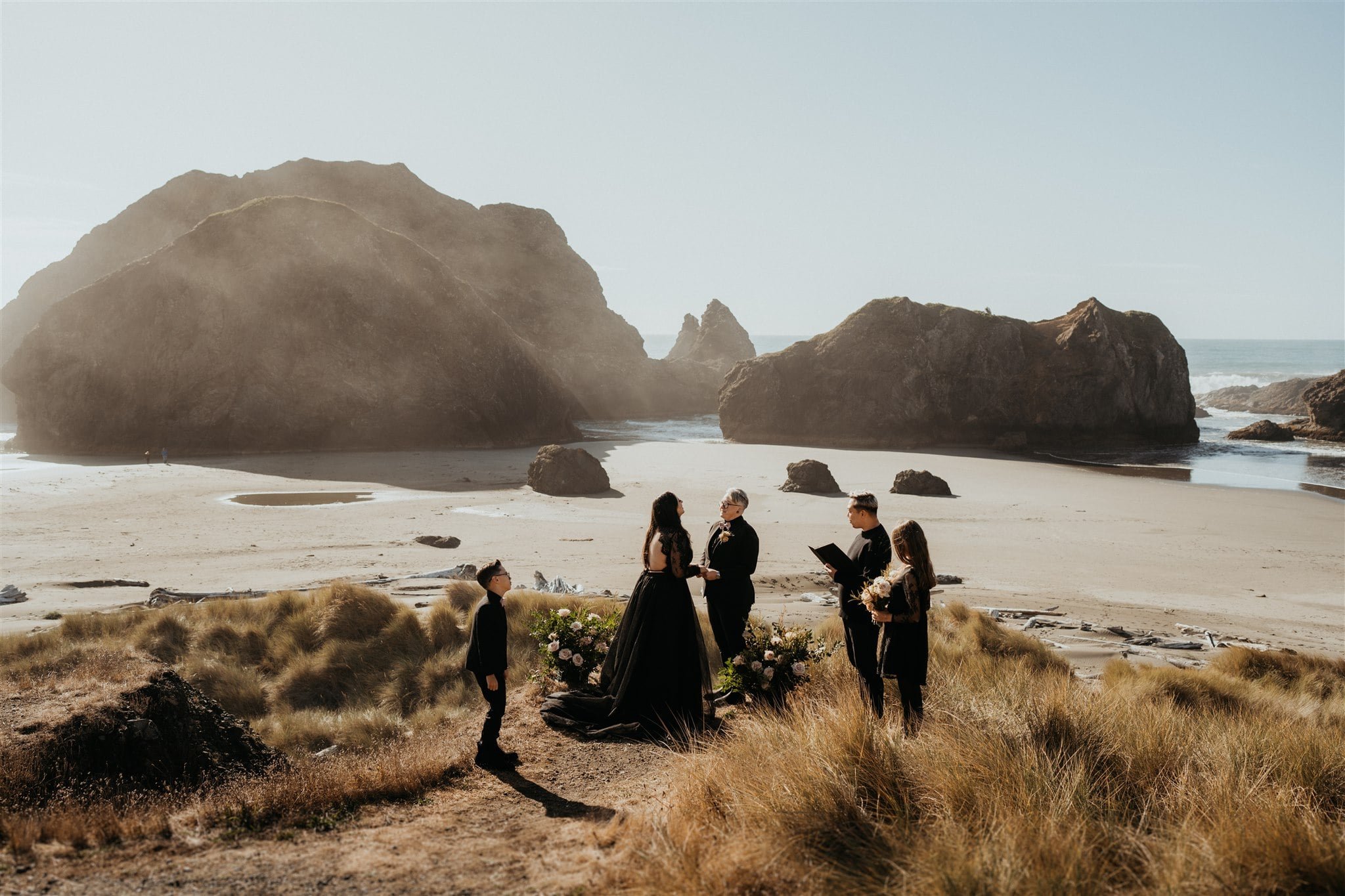 Two brides hold hands during Oregon Coast elopement ceremony on the beach