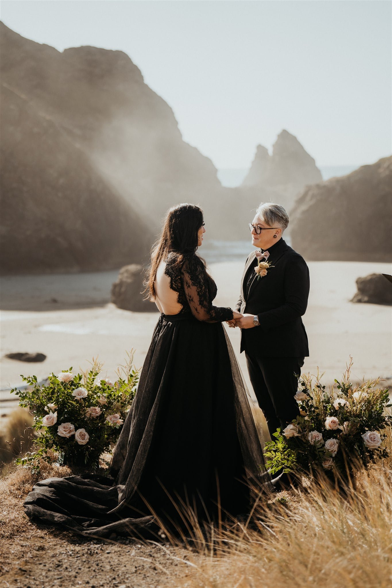 Two brides hold hands during their Pacific Northwest elopement ceremony on the Oregon Coast