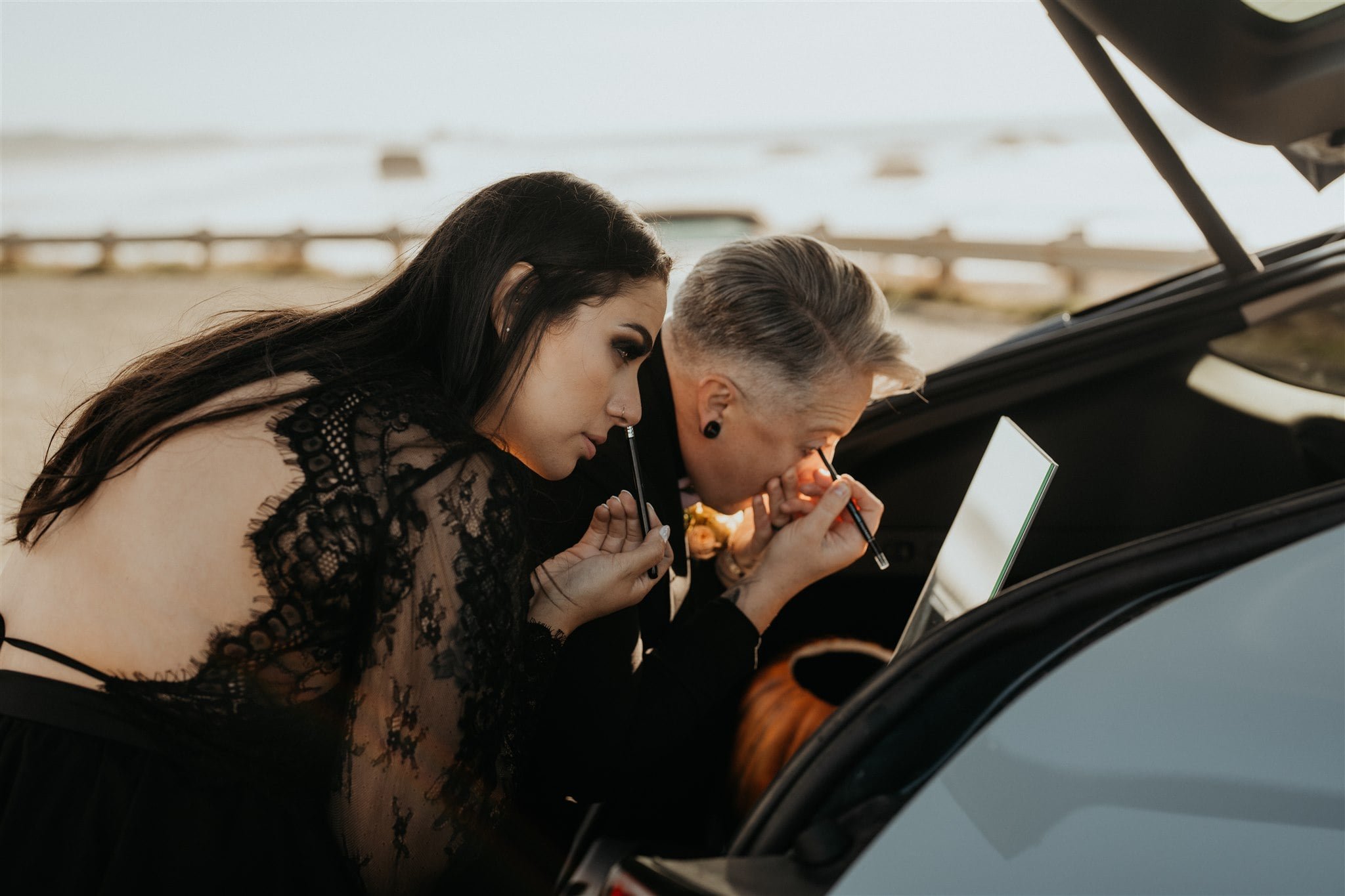 Brides touch up makeup in the car after Pacific Northwest elopement ceremony on the beach