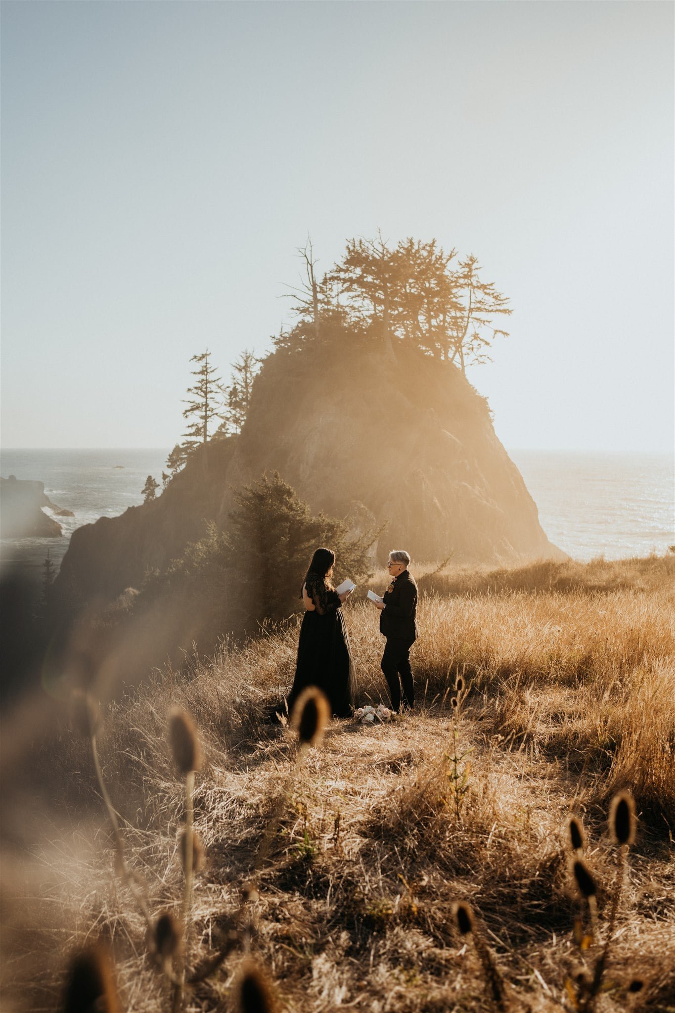 Brides exchange vows on a hill overlooking the ocean during their Pacific Northwest elopement