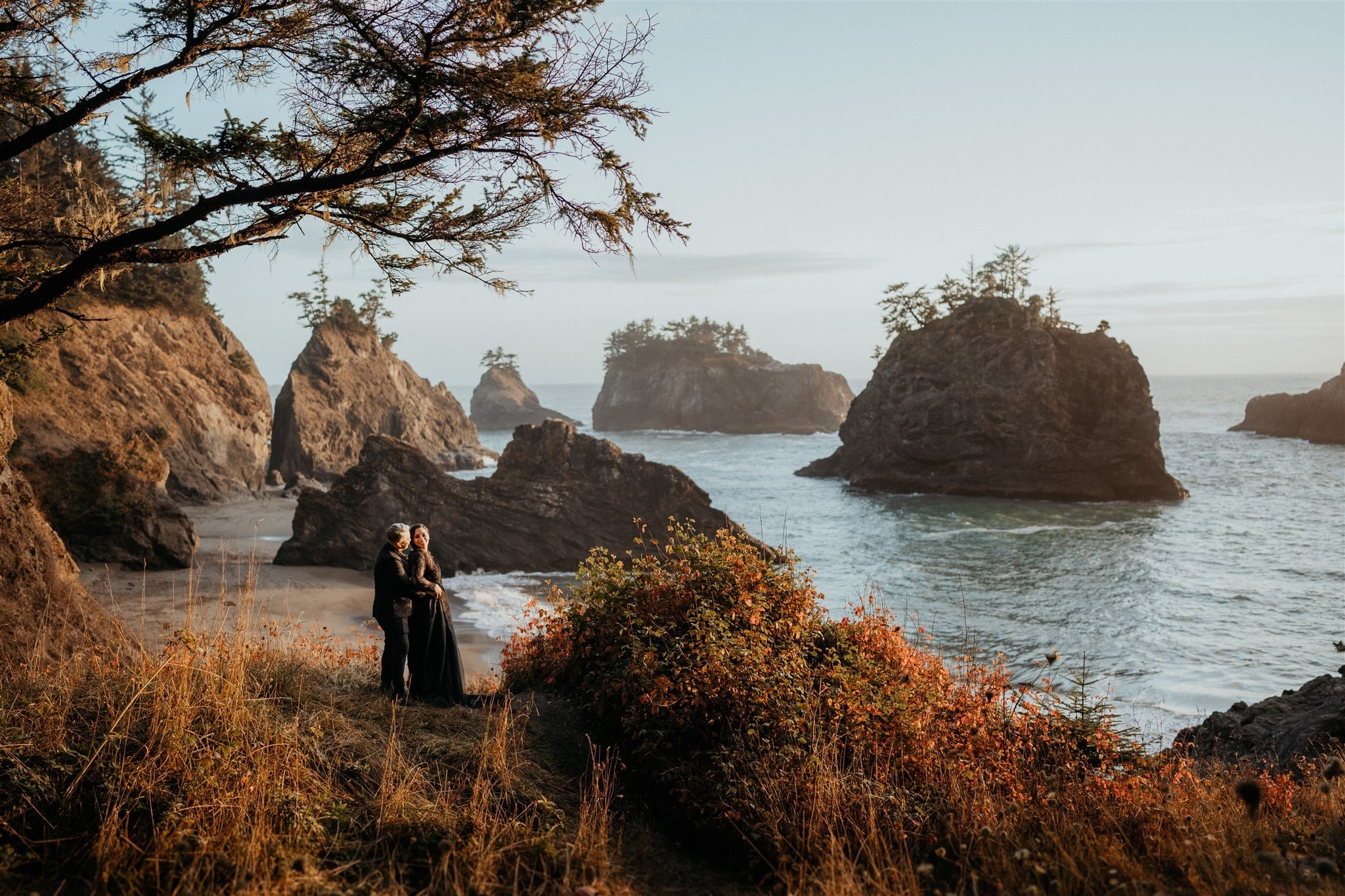 Two brides look out at the ocean during their Pacific Northwest elopement