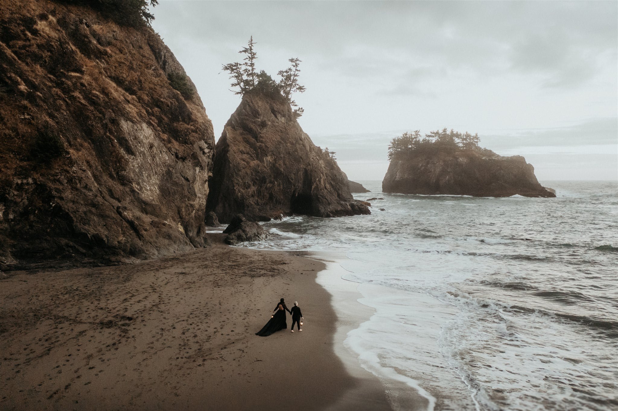 Two brides walk across the beach during their Pacific Northwest elopement