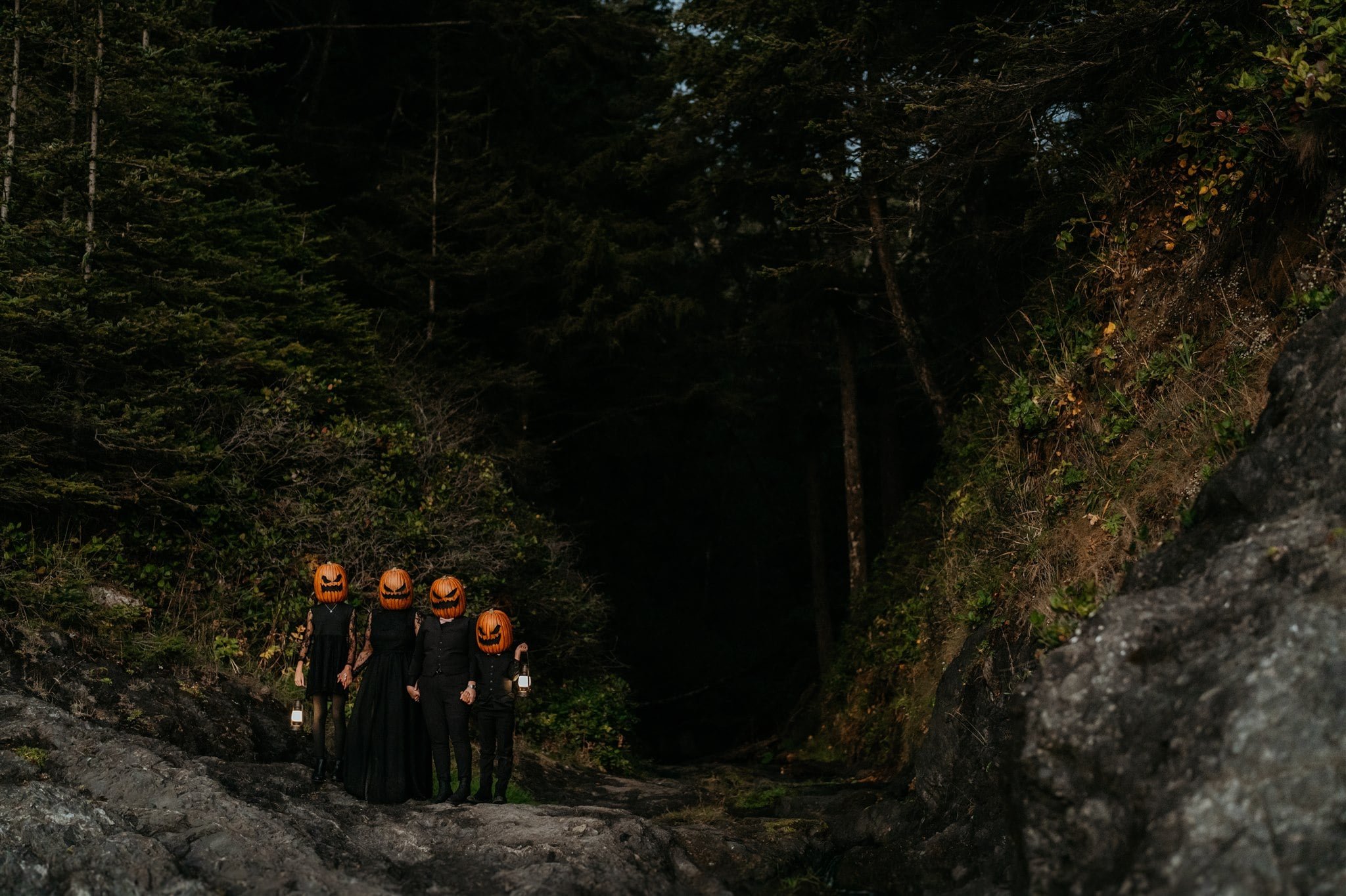 Family wearing all black elopement outfits and pumpkins on the heads during Pacific Northwest elopement photos