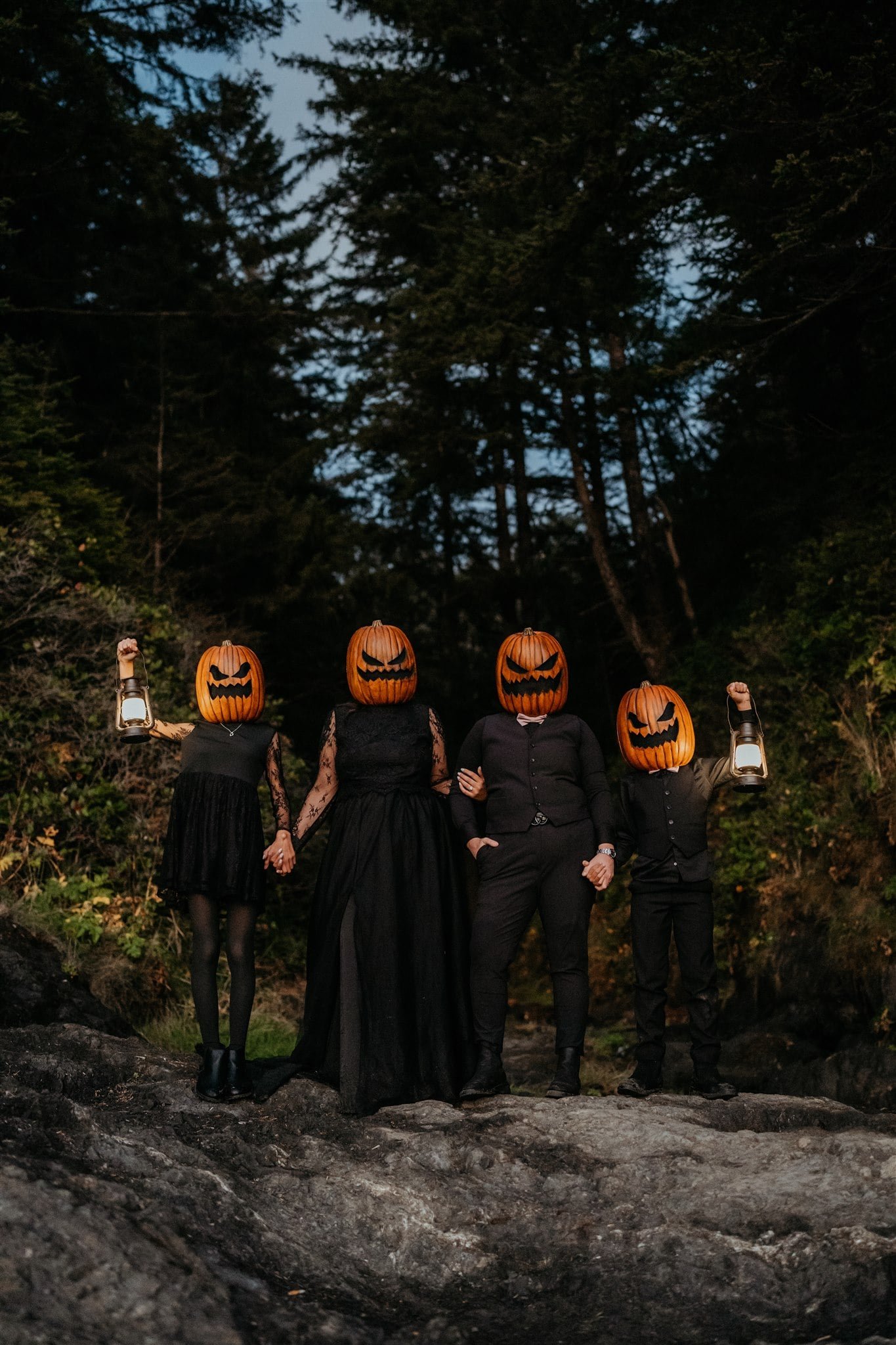 Family wearing all black elopement outfits and pumpkins on the heads during Pacific Northwest elopement photos