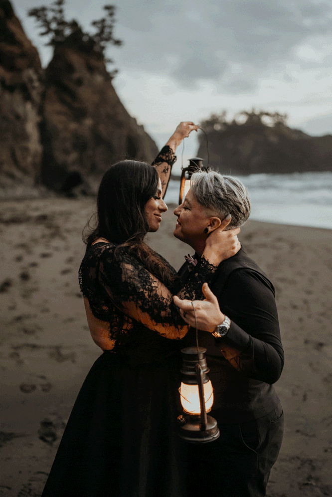 Elopement photos on the beach with two brides wearing all black elopement outfits