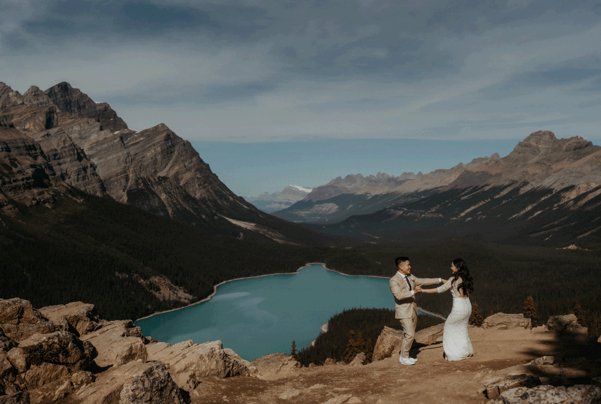 Bride and groom dance on top of a mountain looking out over a lake at their Banff National Park elopement