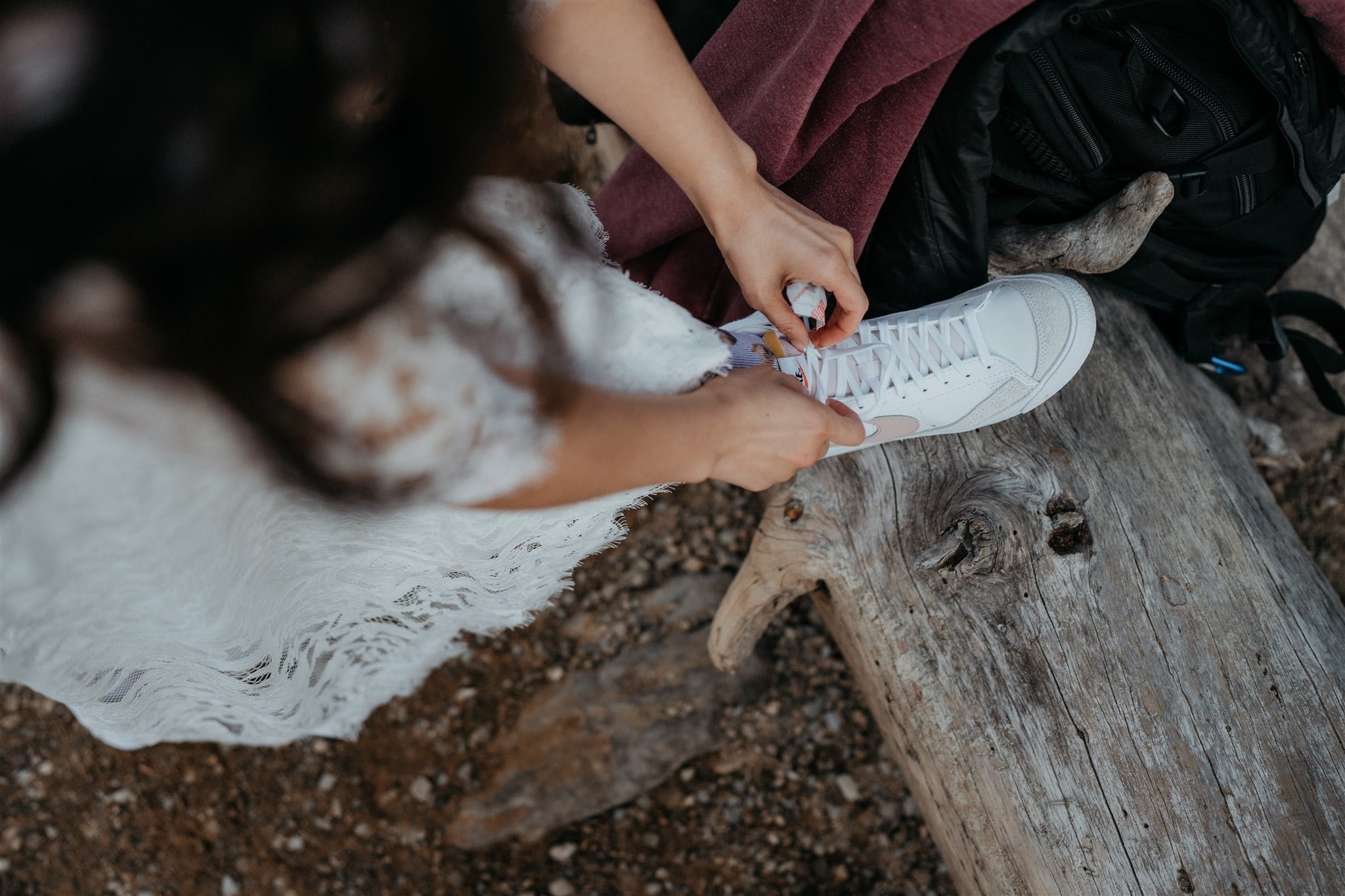 Bride tying white converse while getting ready for elopement in Banff