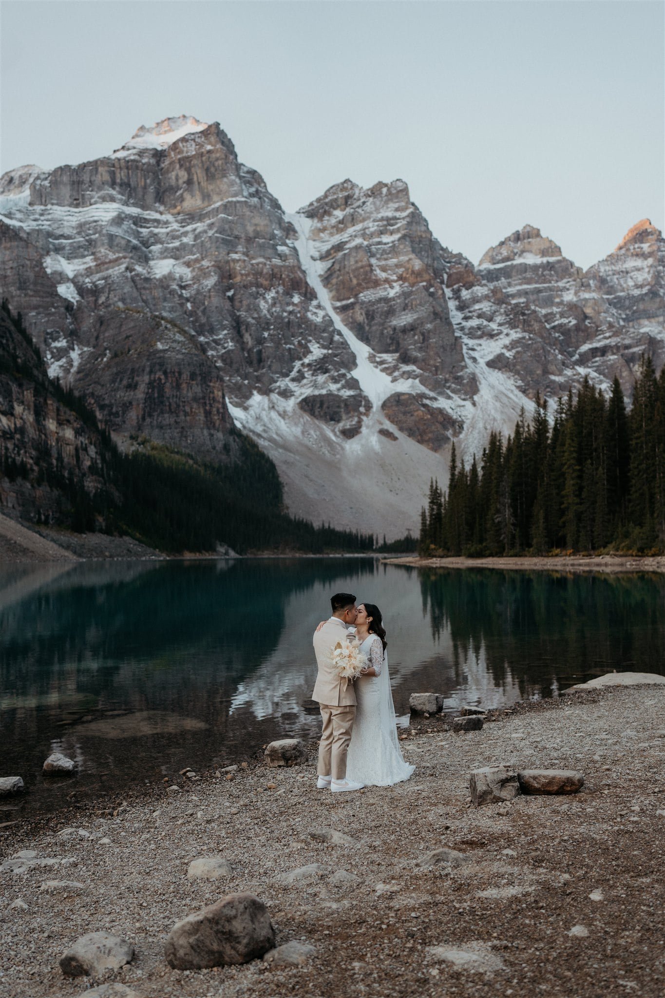 Bride and groom kiss after sunrise first look at Banff National Park