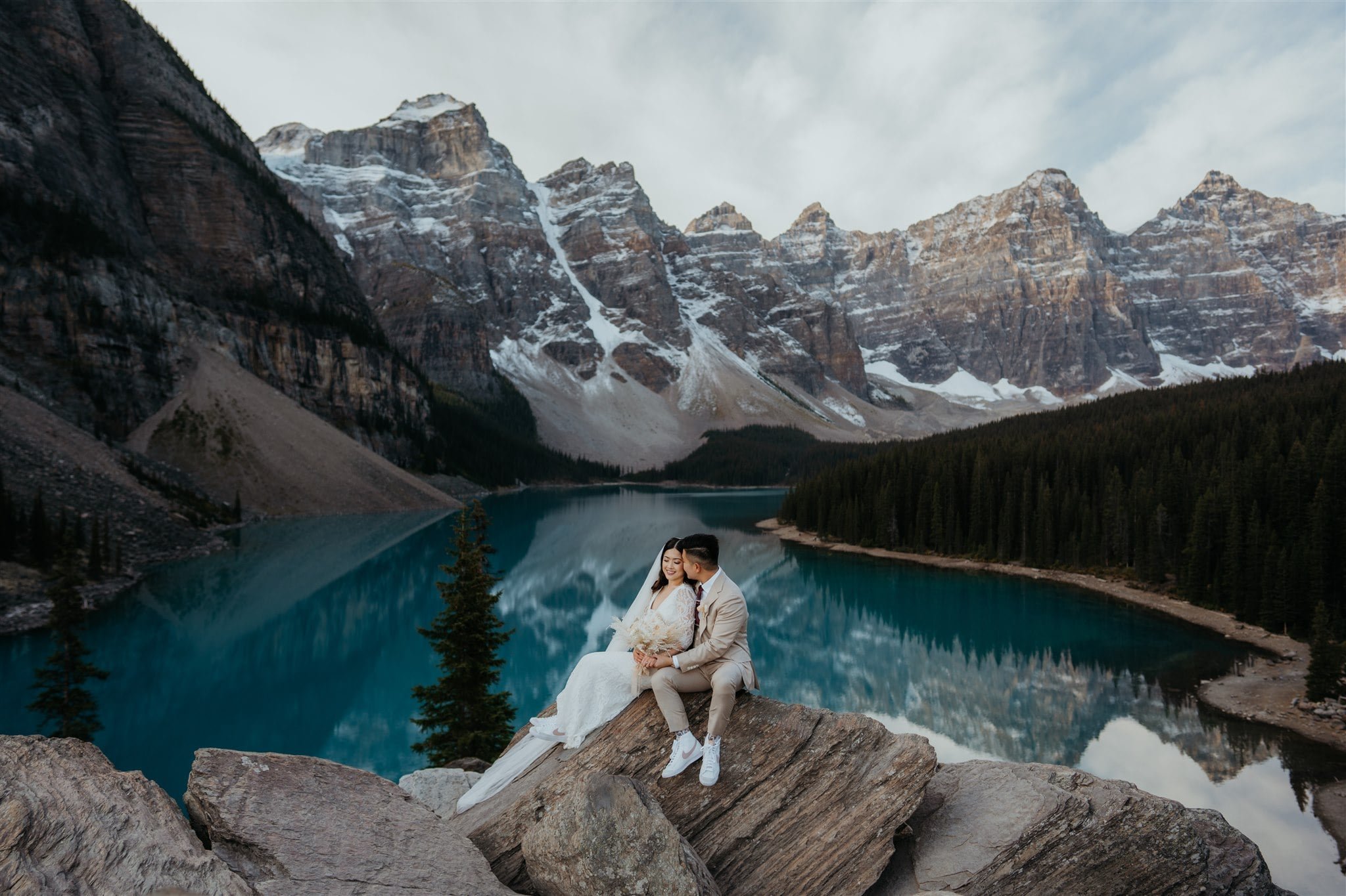 Bride and groom sit on a rock during their sunrise elopement photos at Banff National Park