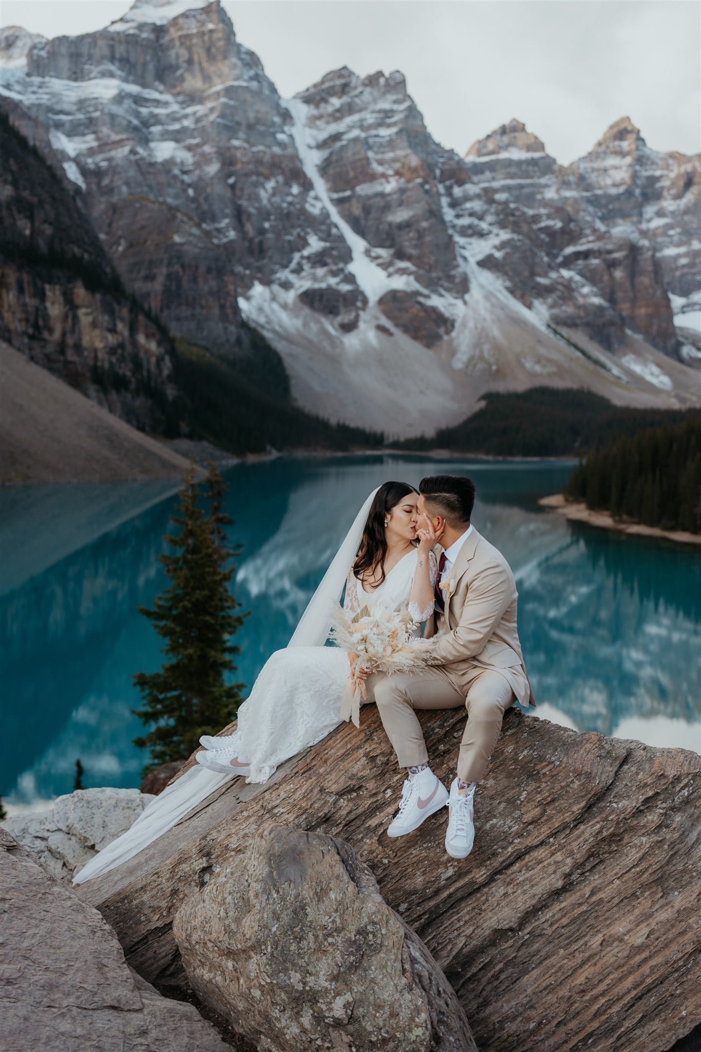 Bride and groom sit on a rock during their sunrise elopement photos at Banff National Park