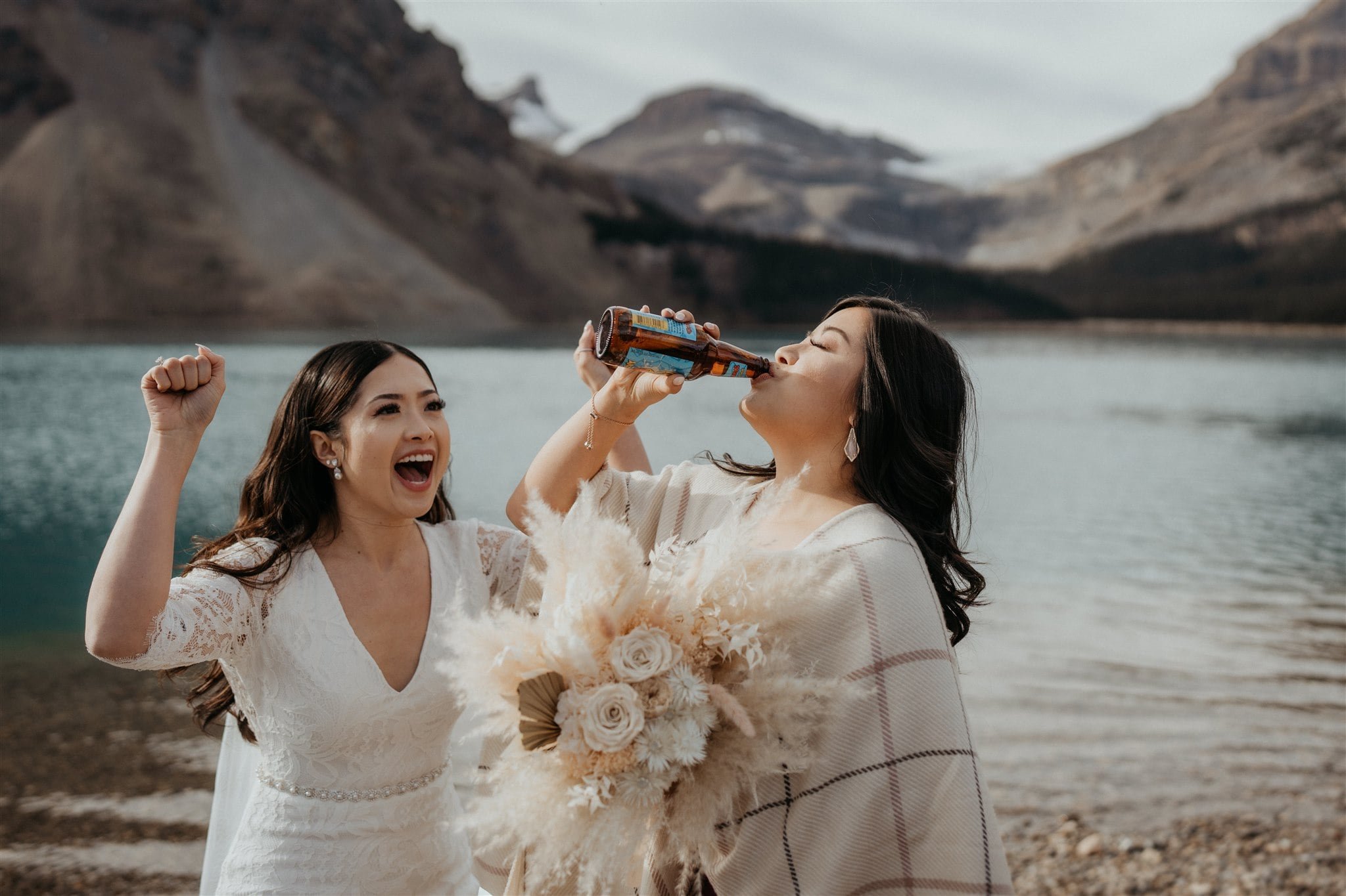 Bride cheers while guest chugs a beer after elopement ceremony in Banff National Park