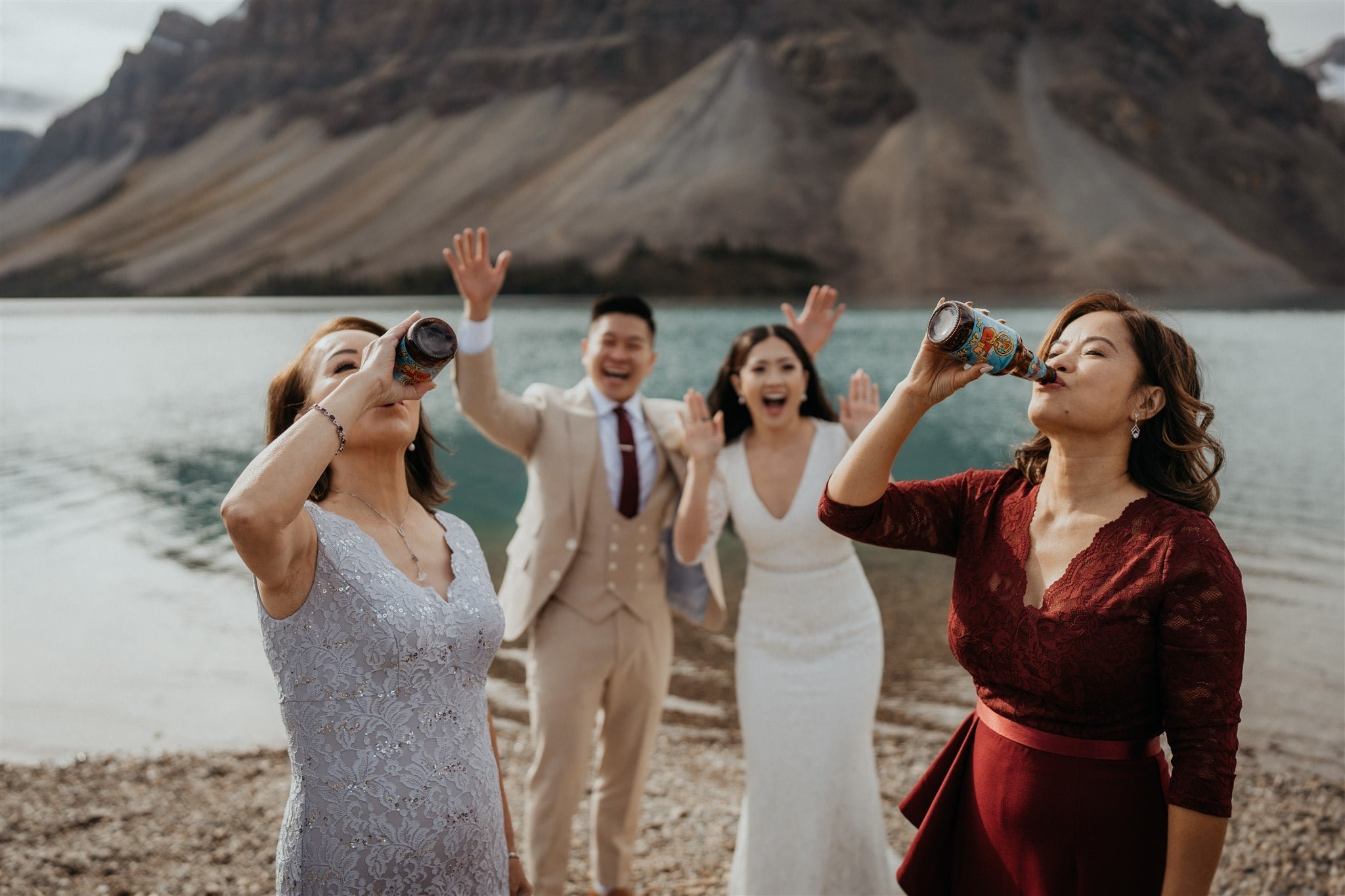 Bride and groom cheer while mothers chug beers after their elopement ceremony in Banff National Park