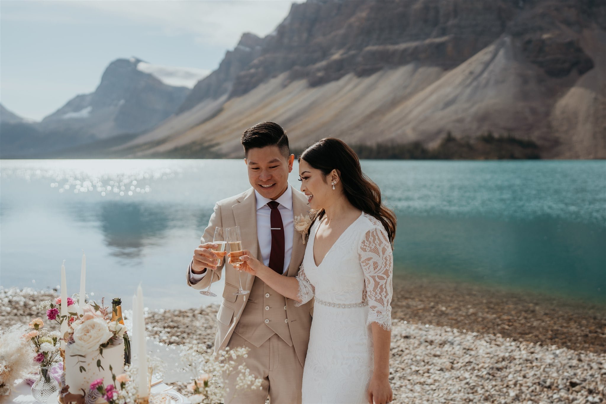 Bride and groom toast with champagne after cutting cake at their Banff National Park elopement