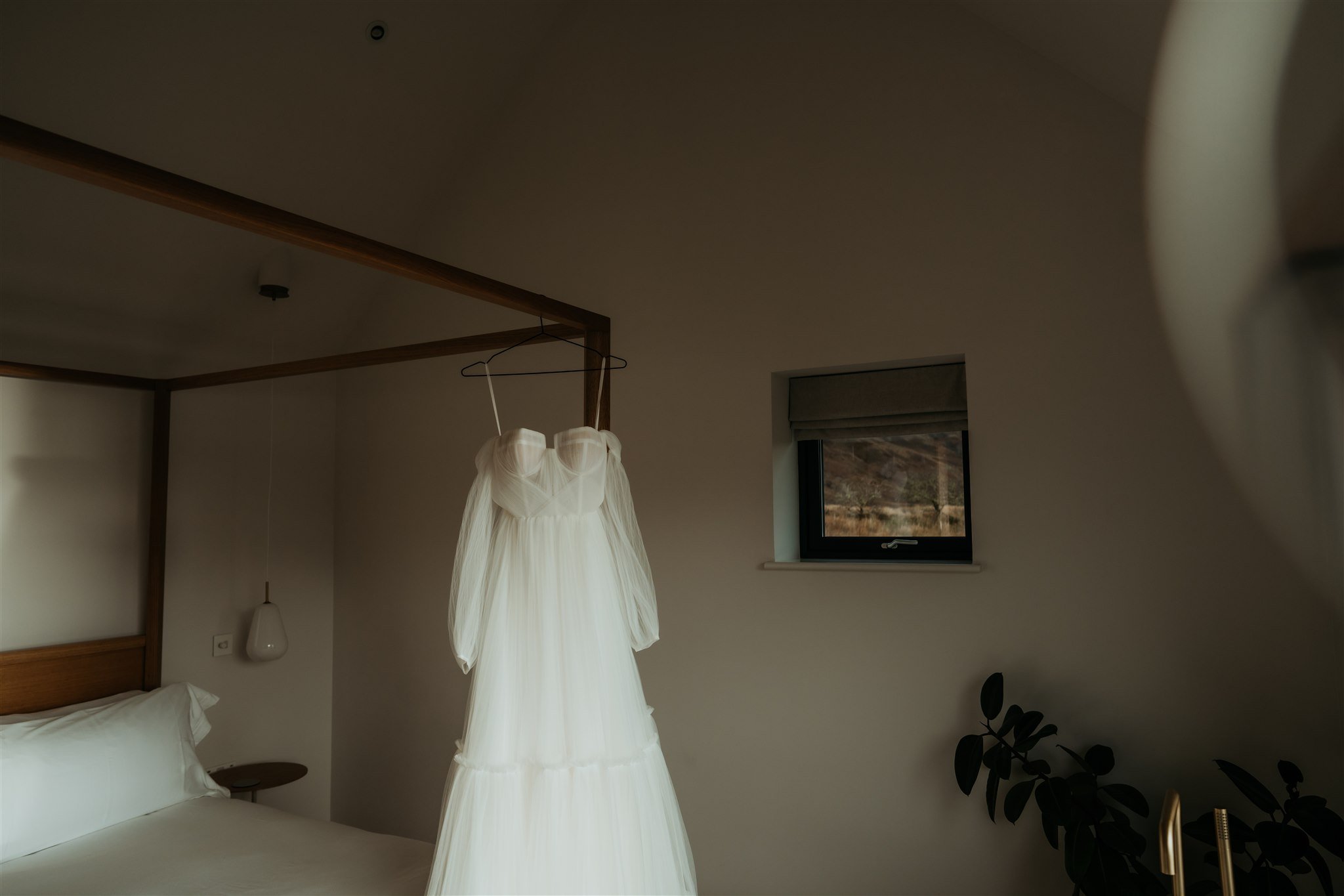 White wedding dress hanging from the bed in the wedding suite on Isle of Skye