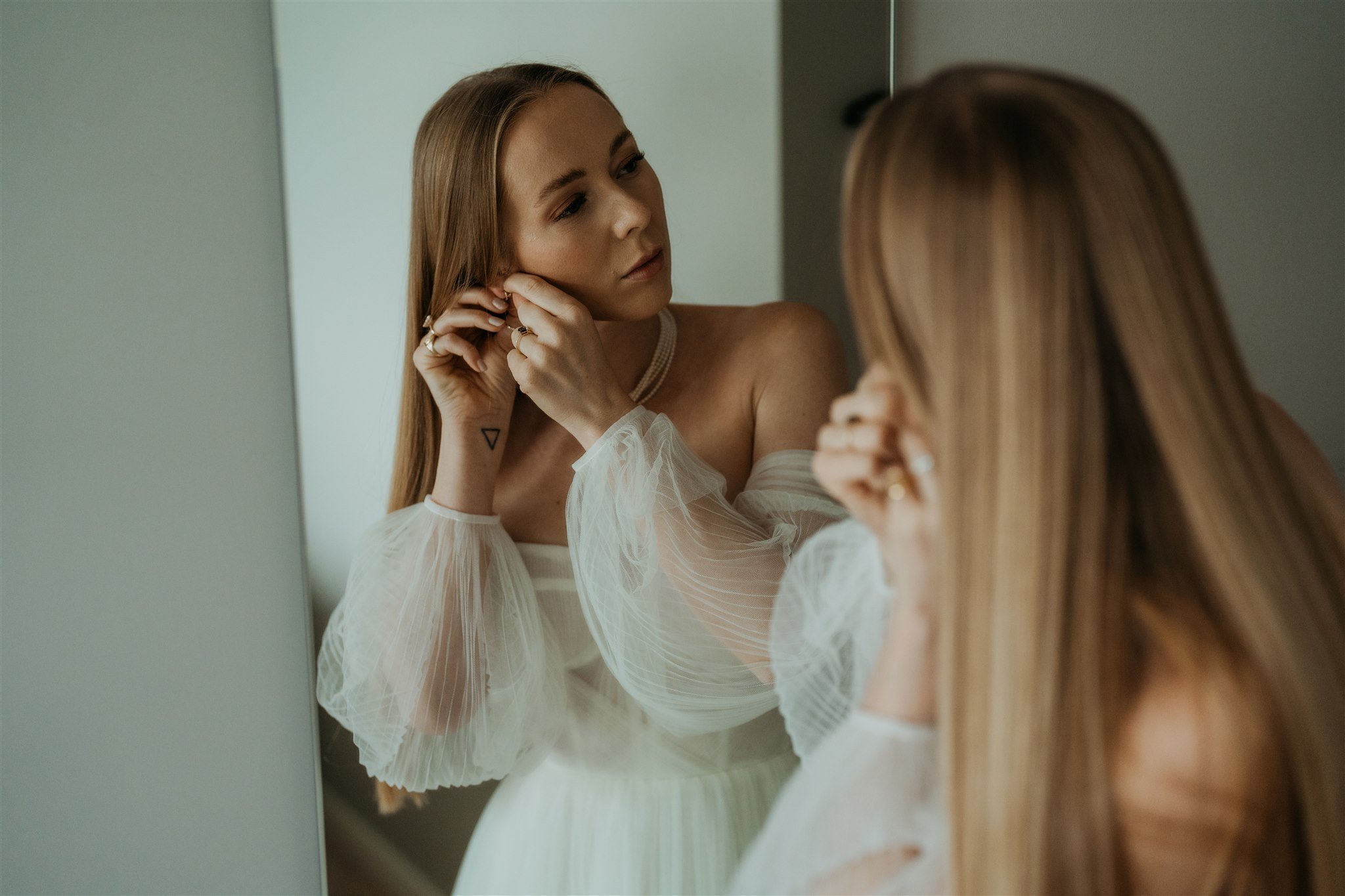 Bride putting on earrings while getting ready for Isle of Skye elopement