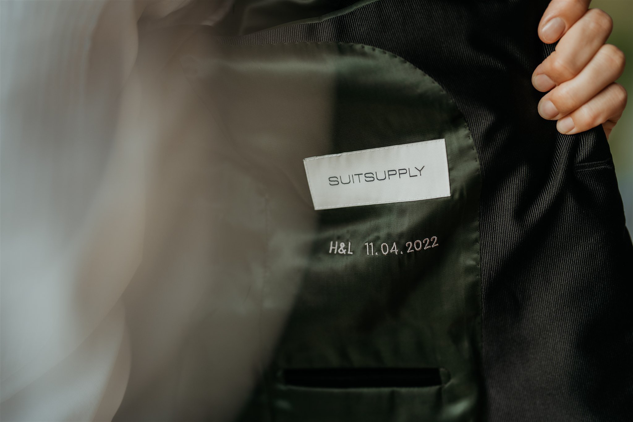 Monogrammed initials and date on the inside of bride's Suit Supply suit coat