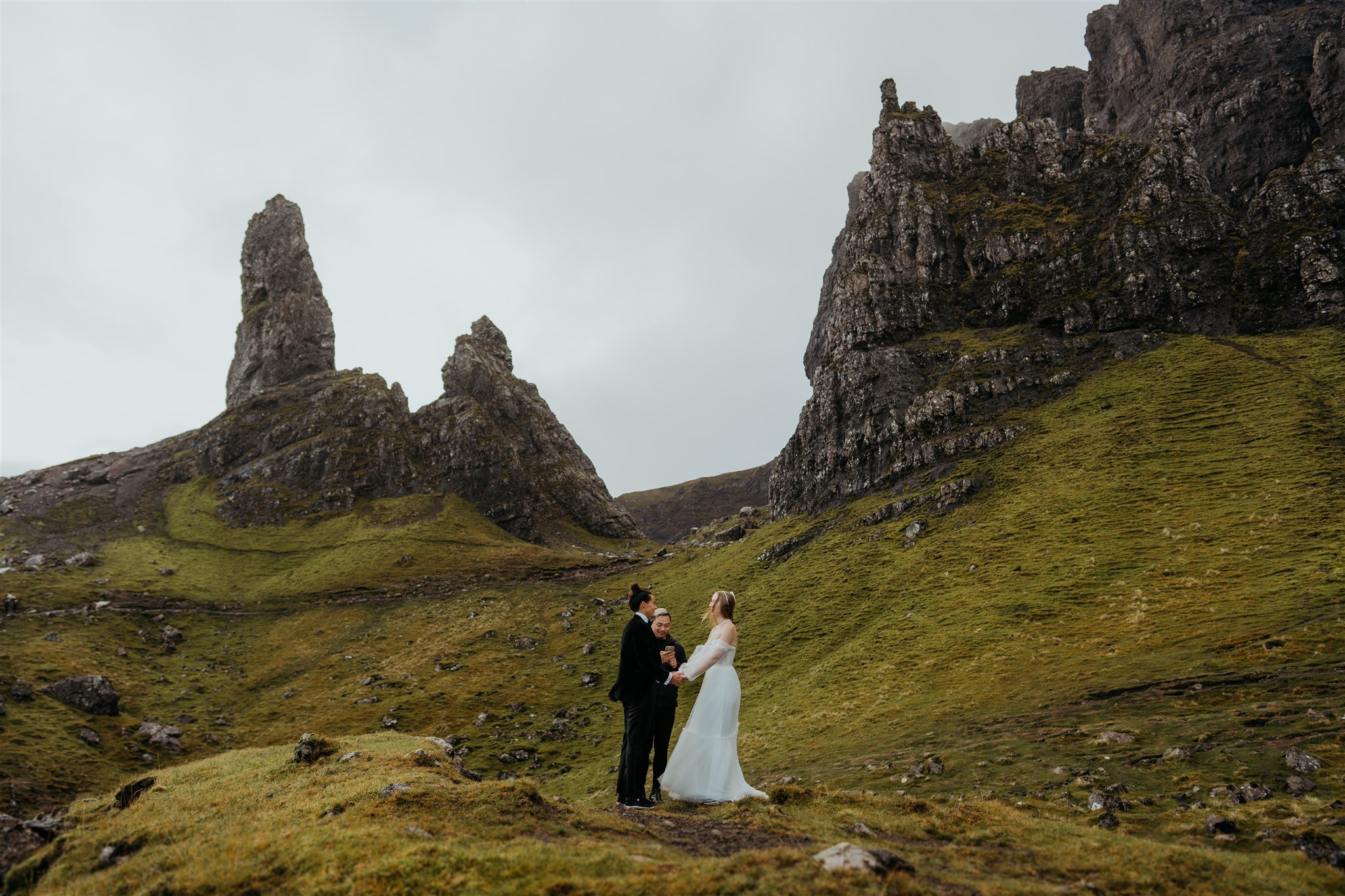 Brides stand on a mossy hill during their Isle of Skye elopement