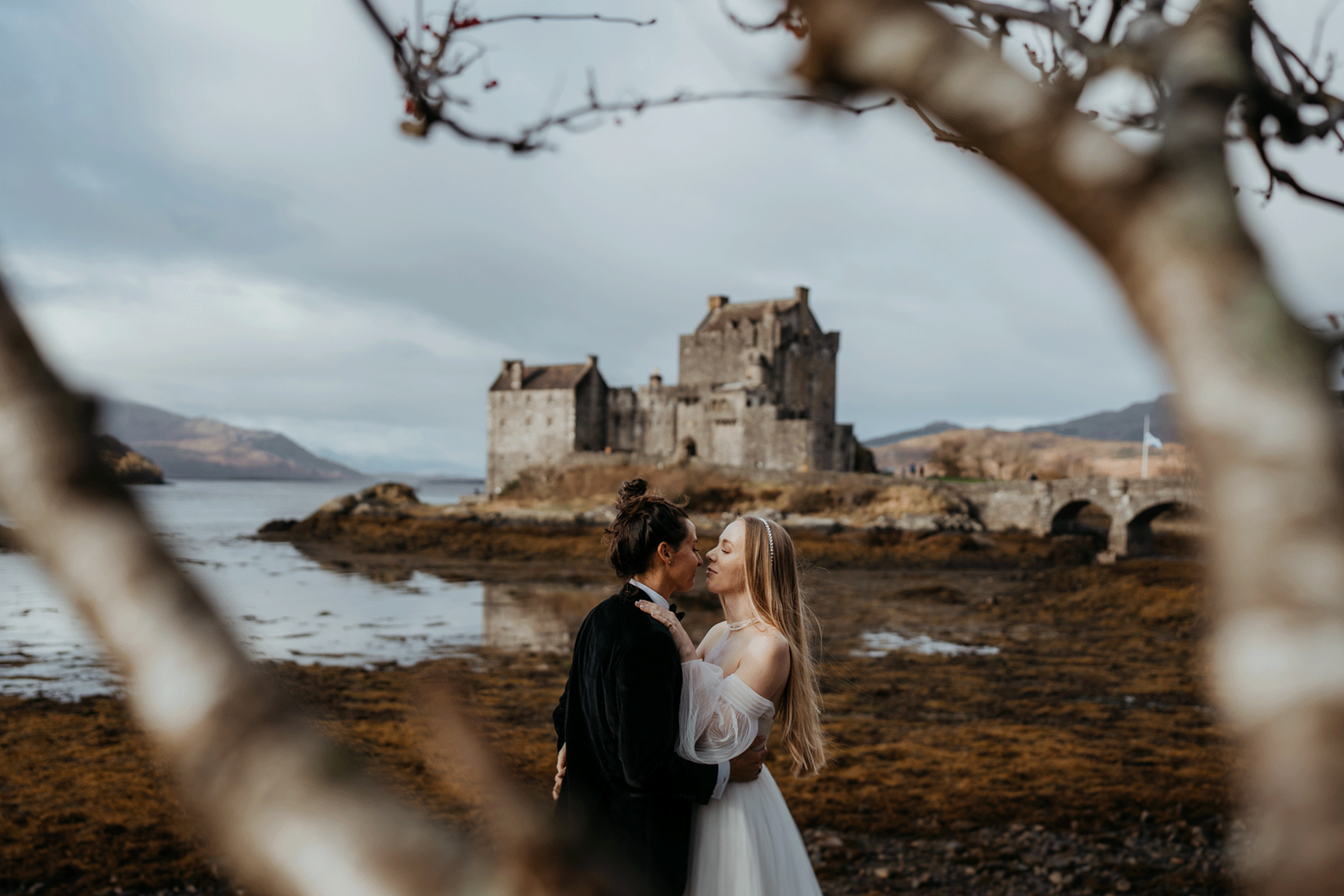 Brides kiss in front of a castle on the Isle of Skye