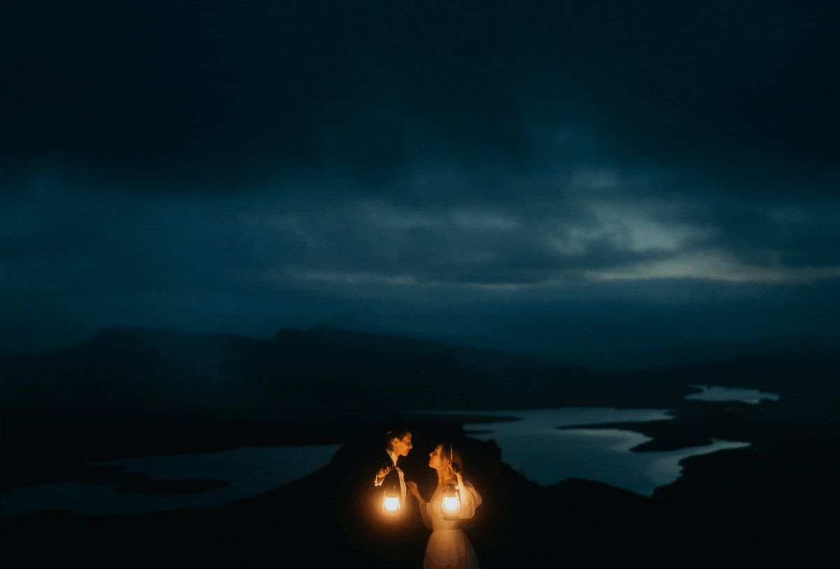 Brides kiss while holding lanterns during blue hour elopement photos on the Isle of Skye