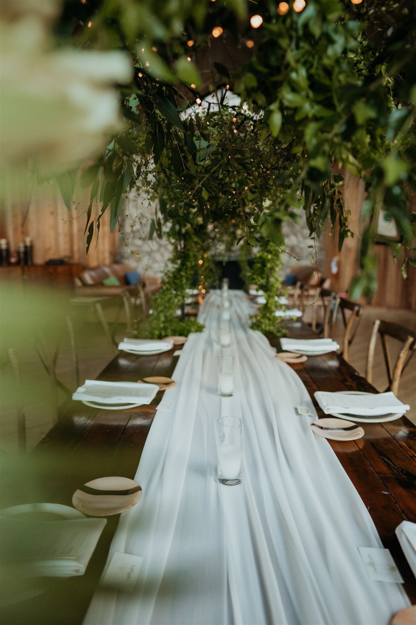 Winter wedding reception table with greenery arch and white table runner