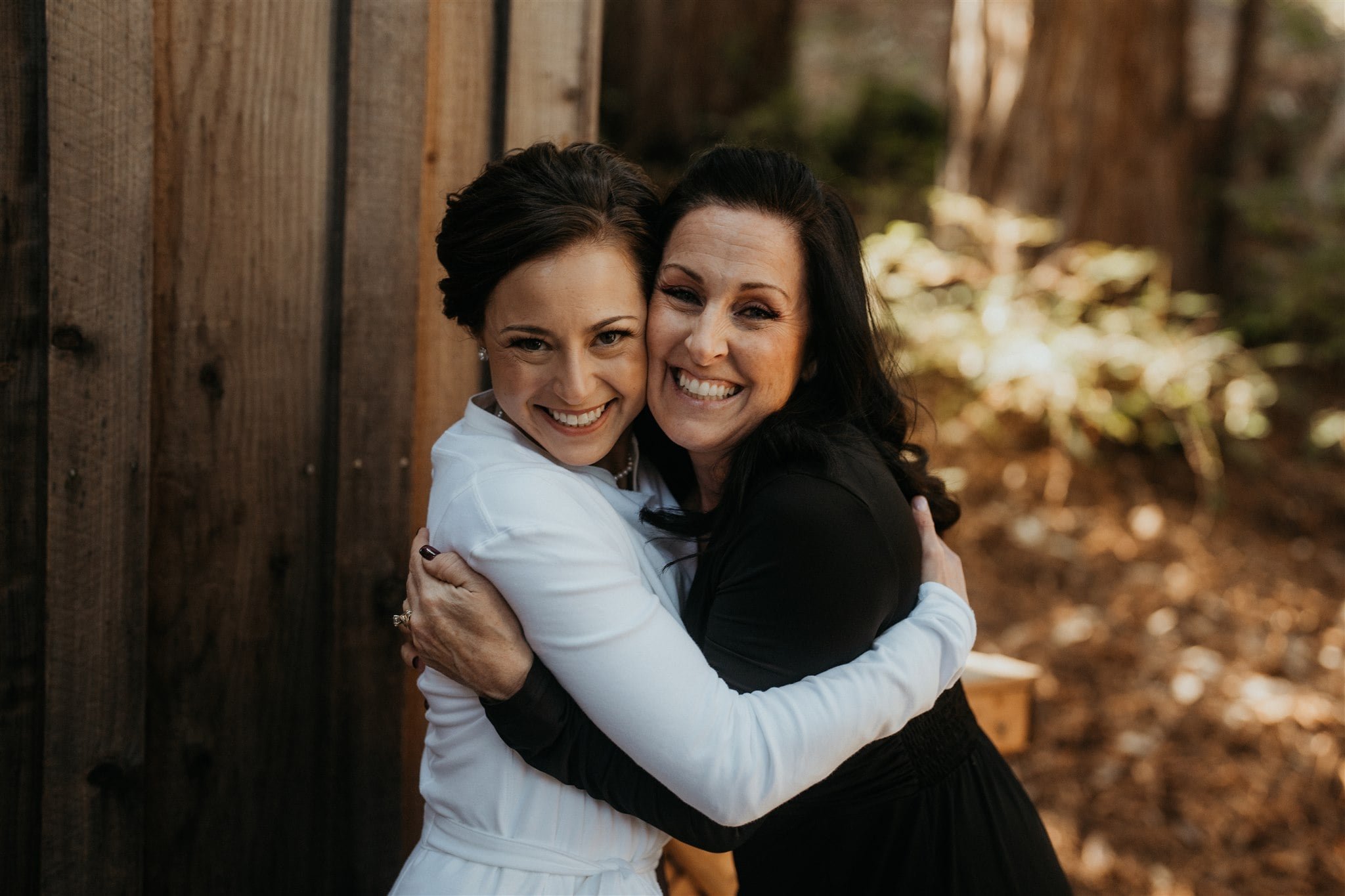 Bride hugging guest while getting ready for winter wedding at Sequoia Retreat Center