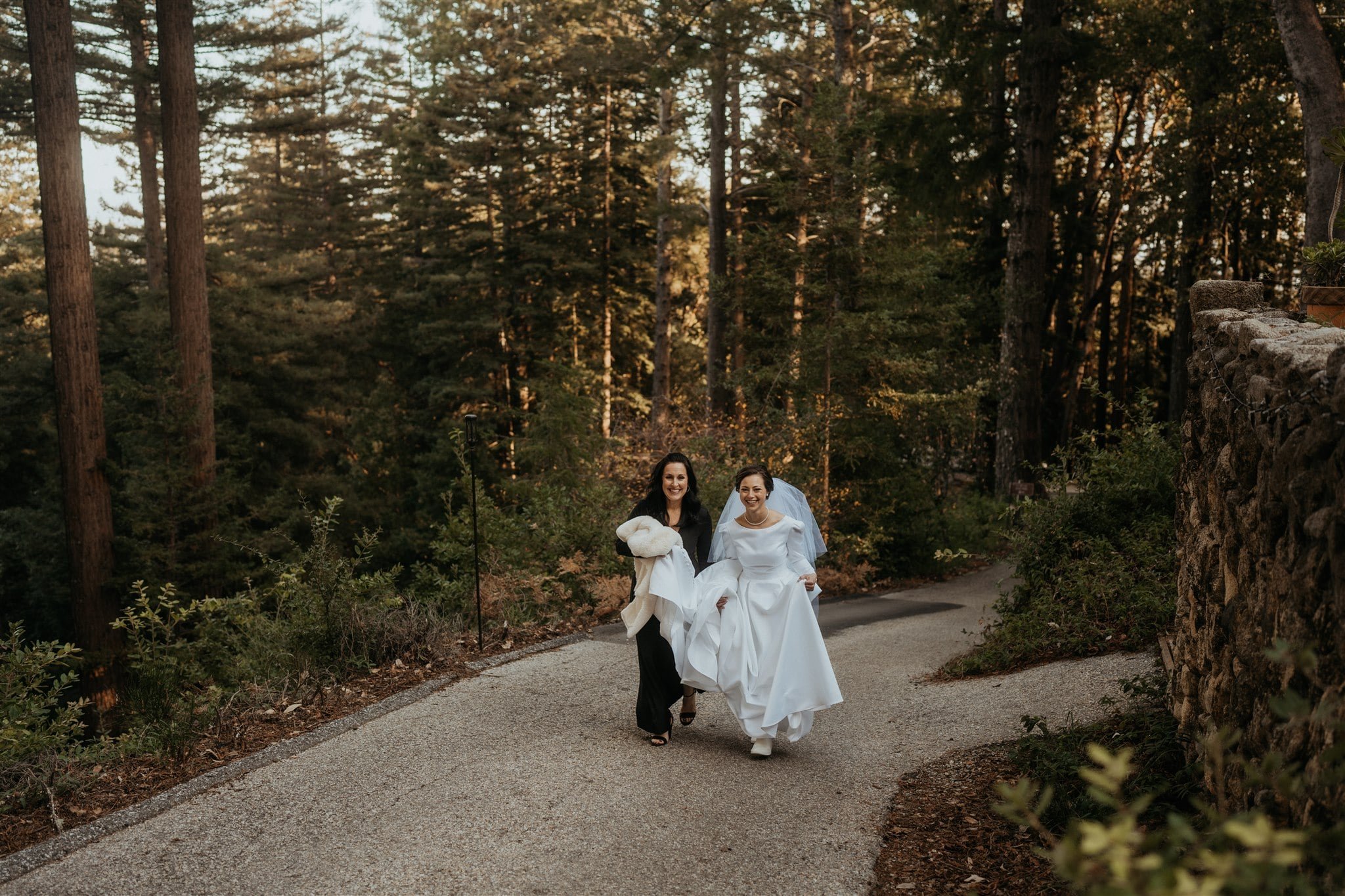 Bride holding dress while walking to ceremony location at Sequoia Retreat Center