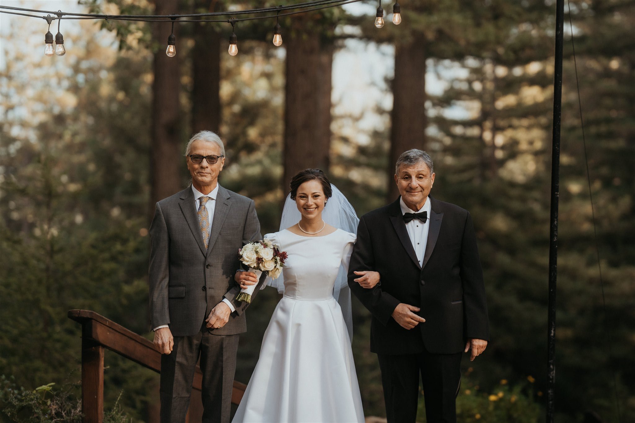 Bride walking down the wedding aisle with two fathers 