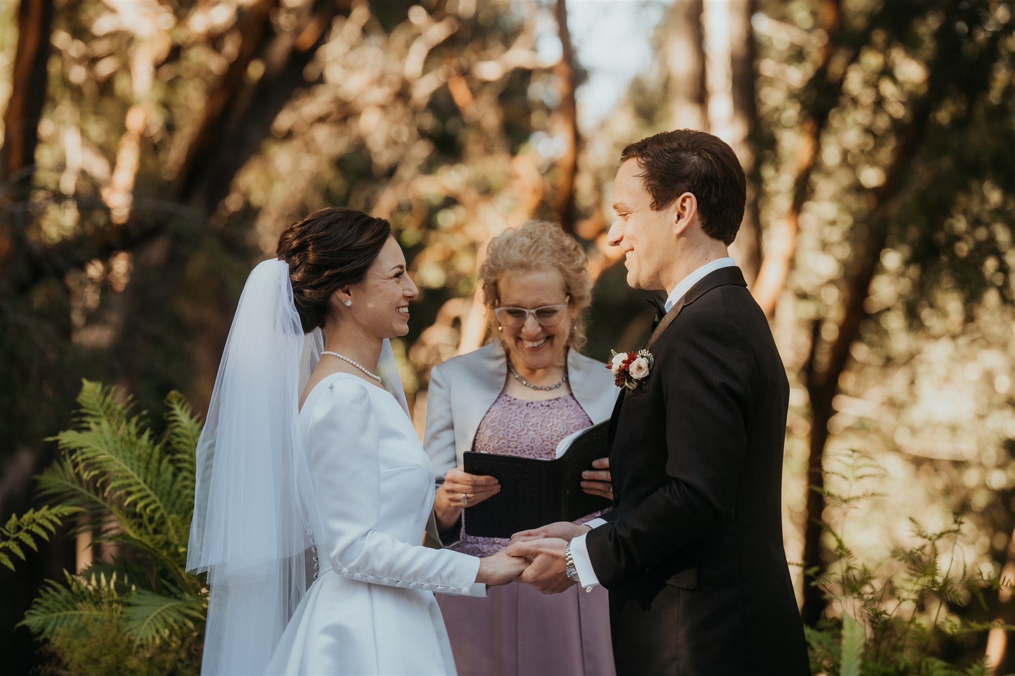 Bride and groom hold hands at their winter wedding ceremony at Sequoia Retreat Center