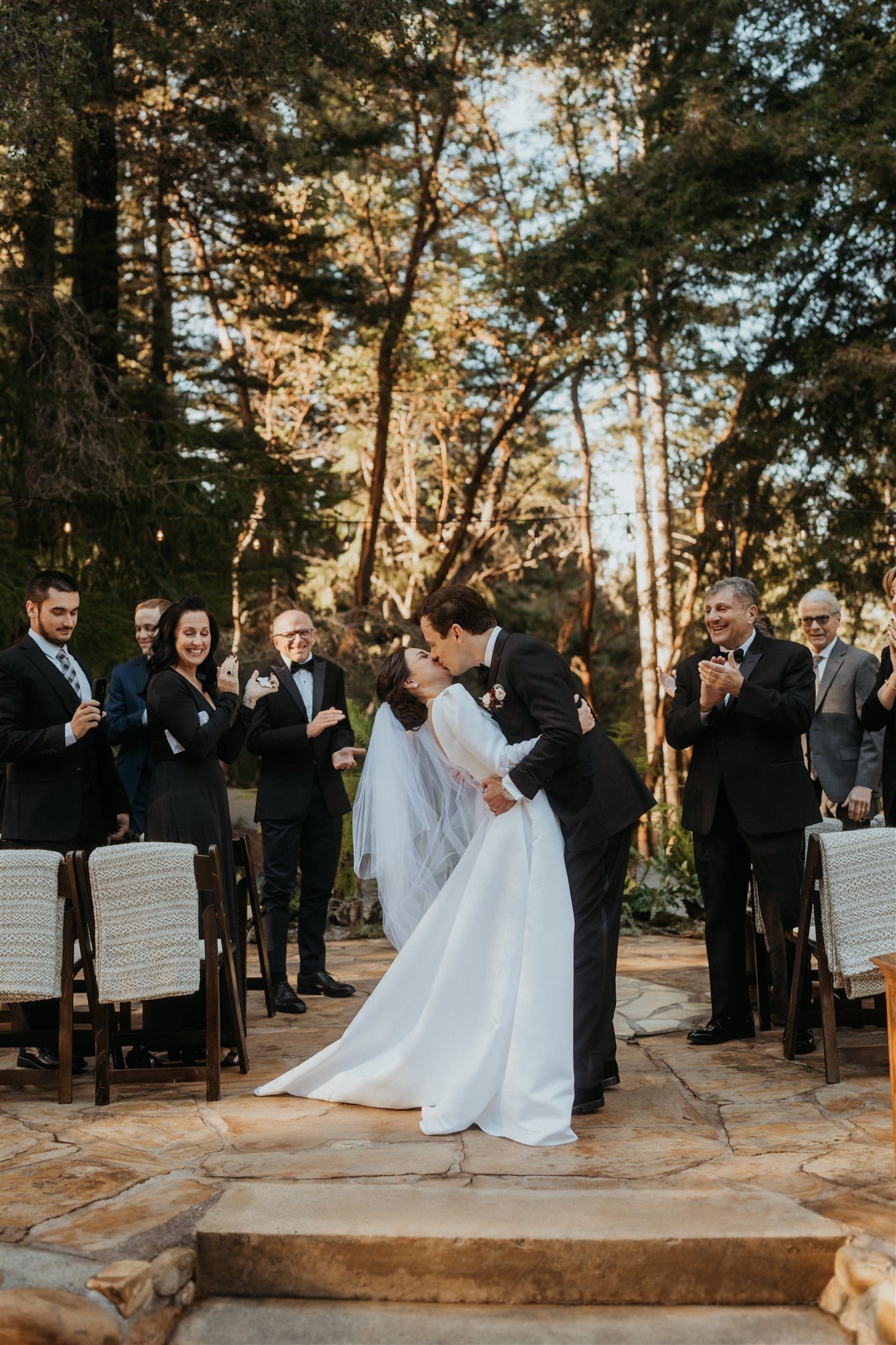 Groom dips bride for a kiss after winter wedding ceremony at Sequoia Retreat Center