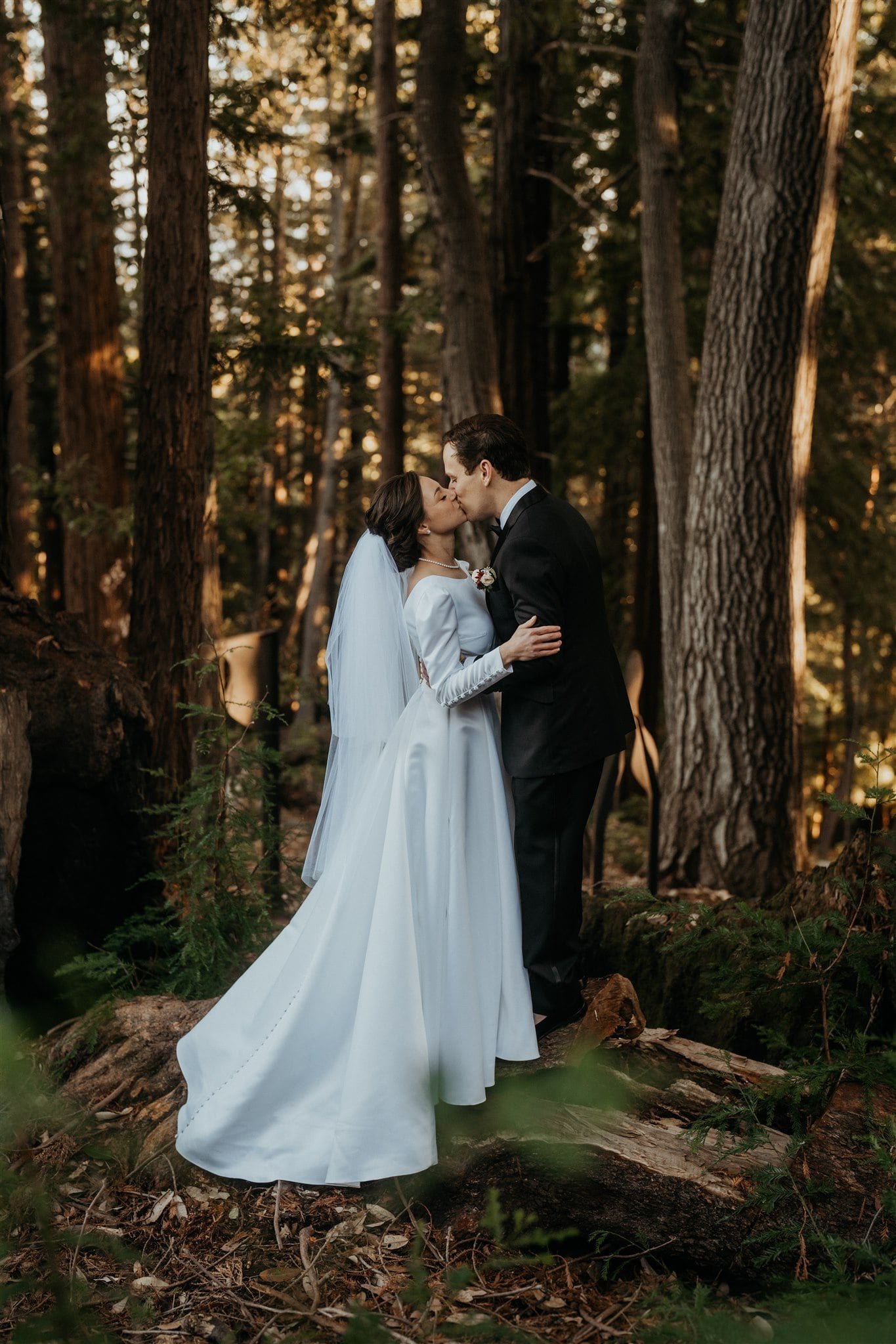 Bride and groom kiss in the forest at Sequoia Retreat Center