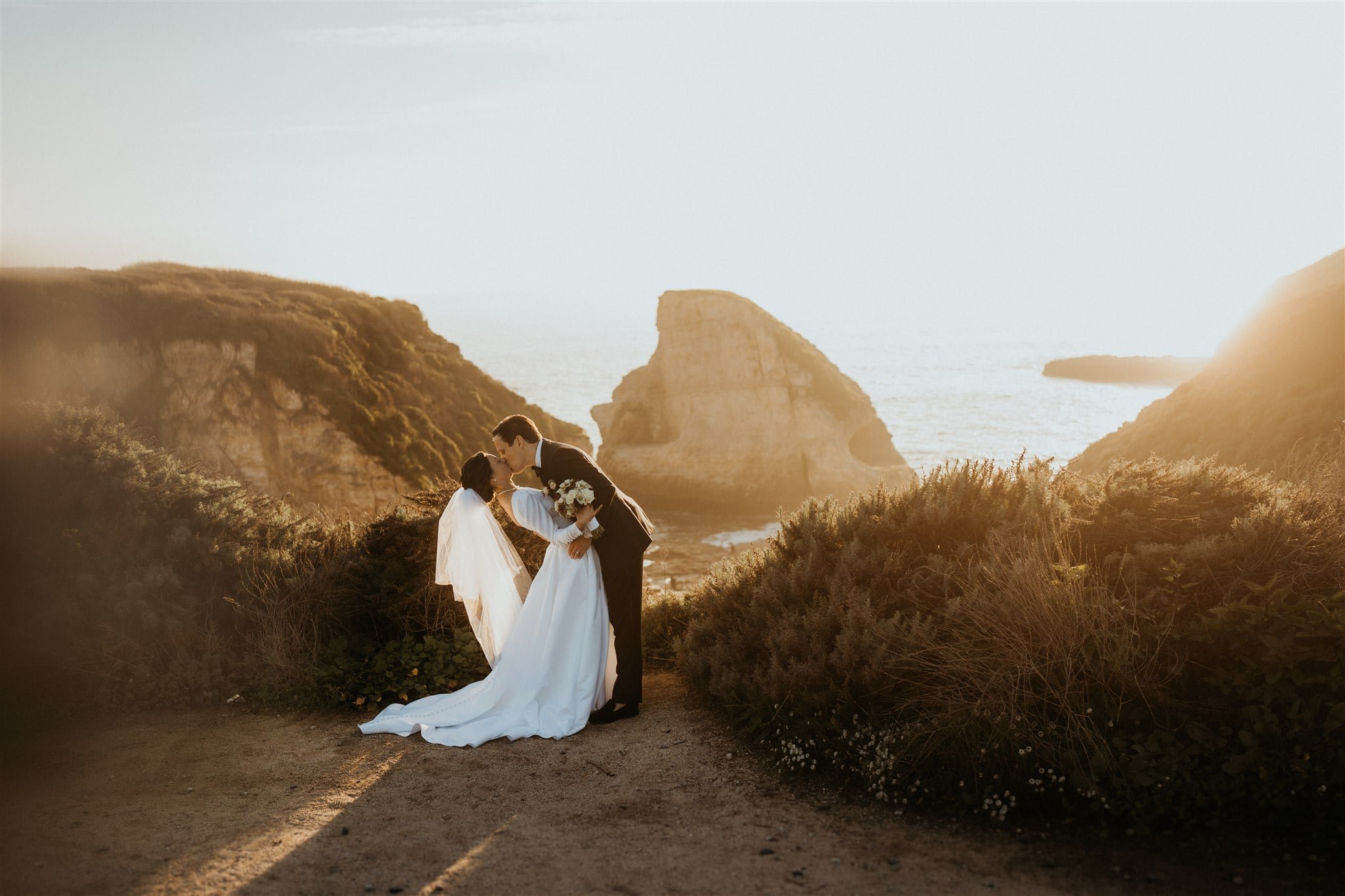 Bride and groom dip for a kiss during California micro wedding portraits at sunset