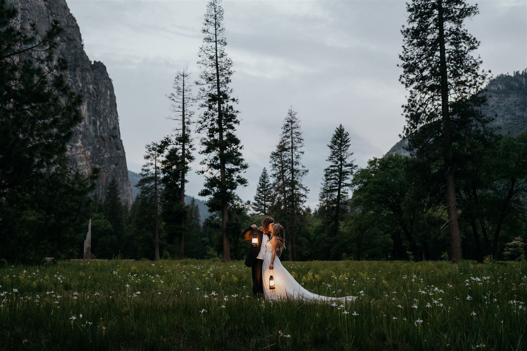 Bride and groom carrying lanterns through El Capitan meadow during their Yosemite elopement