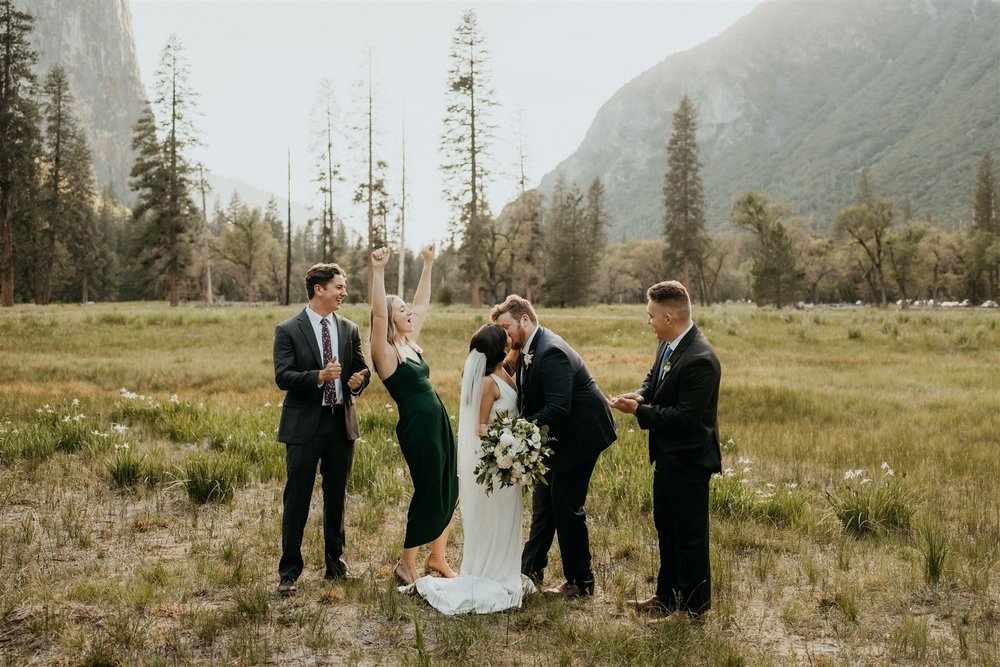 Bride and groom kiss at their El Capitan Meadow elopement while loved ones cheer