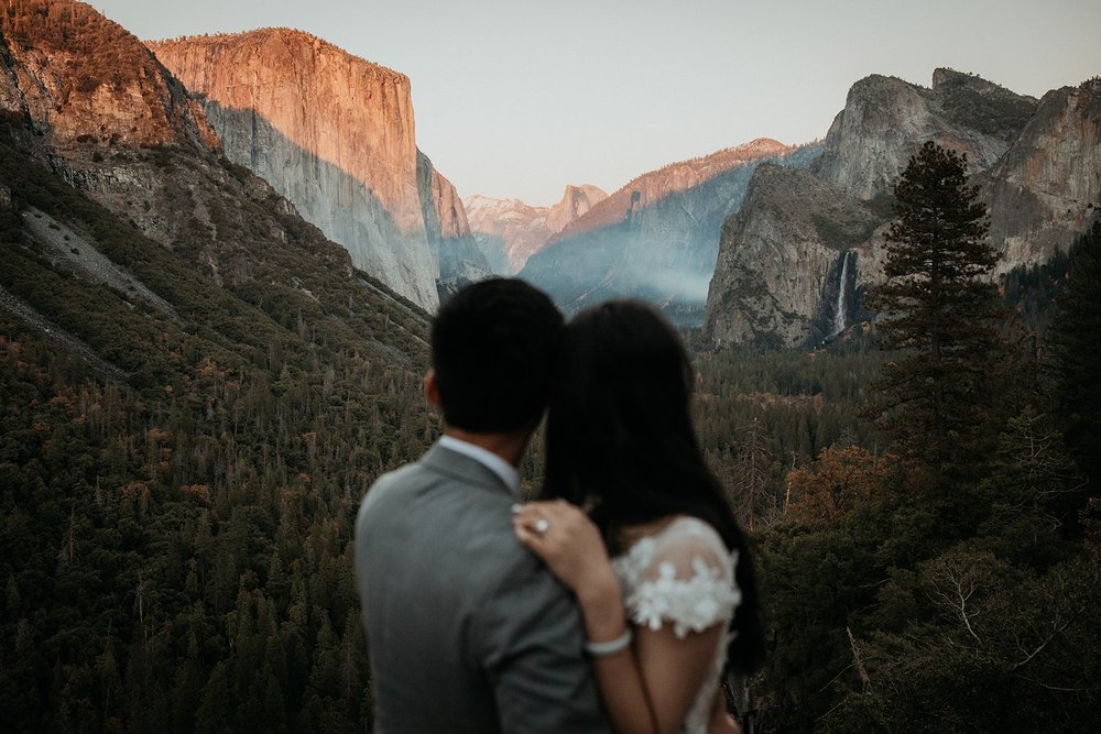 Bride and groom hug while looking out over the lookout at Tunnel View in Yosemite