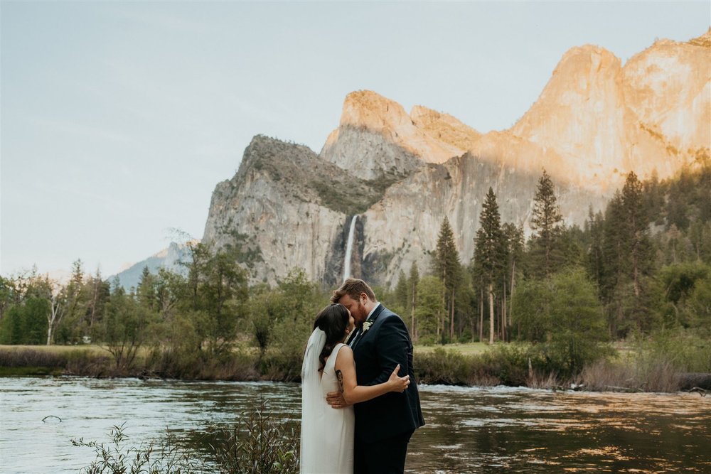 Bride and groom kiss by the lake at their Yosemite elopement