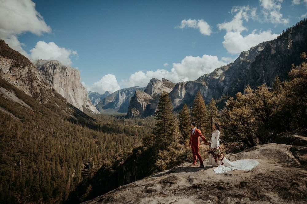 Bride and groom hold hands while walking around during their Tunnel View elopement