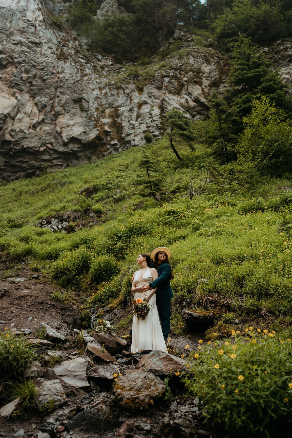 Two brides stand on a grassy hillside during their Columbia River Gorge elopement