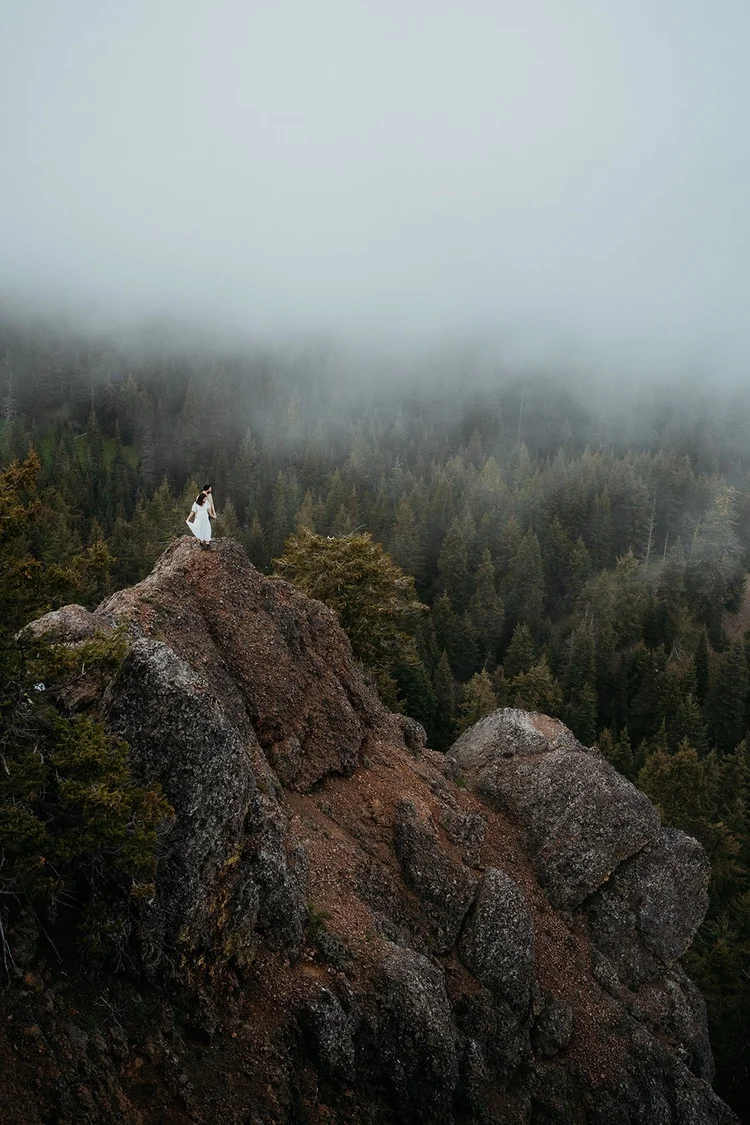 Couple stands on a mountain cliff overlooking Snoqualmie Valley for their elopement in Washington