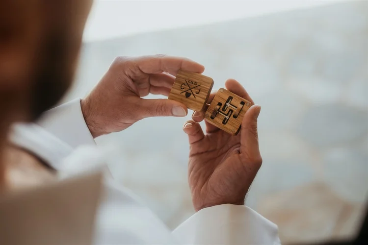 Groom opening custom cuff links while getting ready for Hawaii elopement