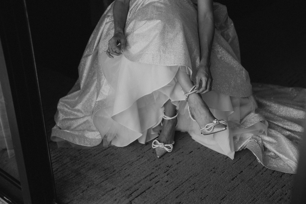 Bride putting on pointed toe silver heels for her Hawaii elopement