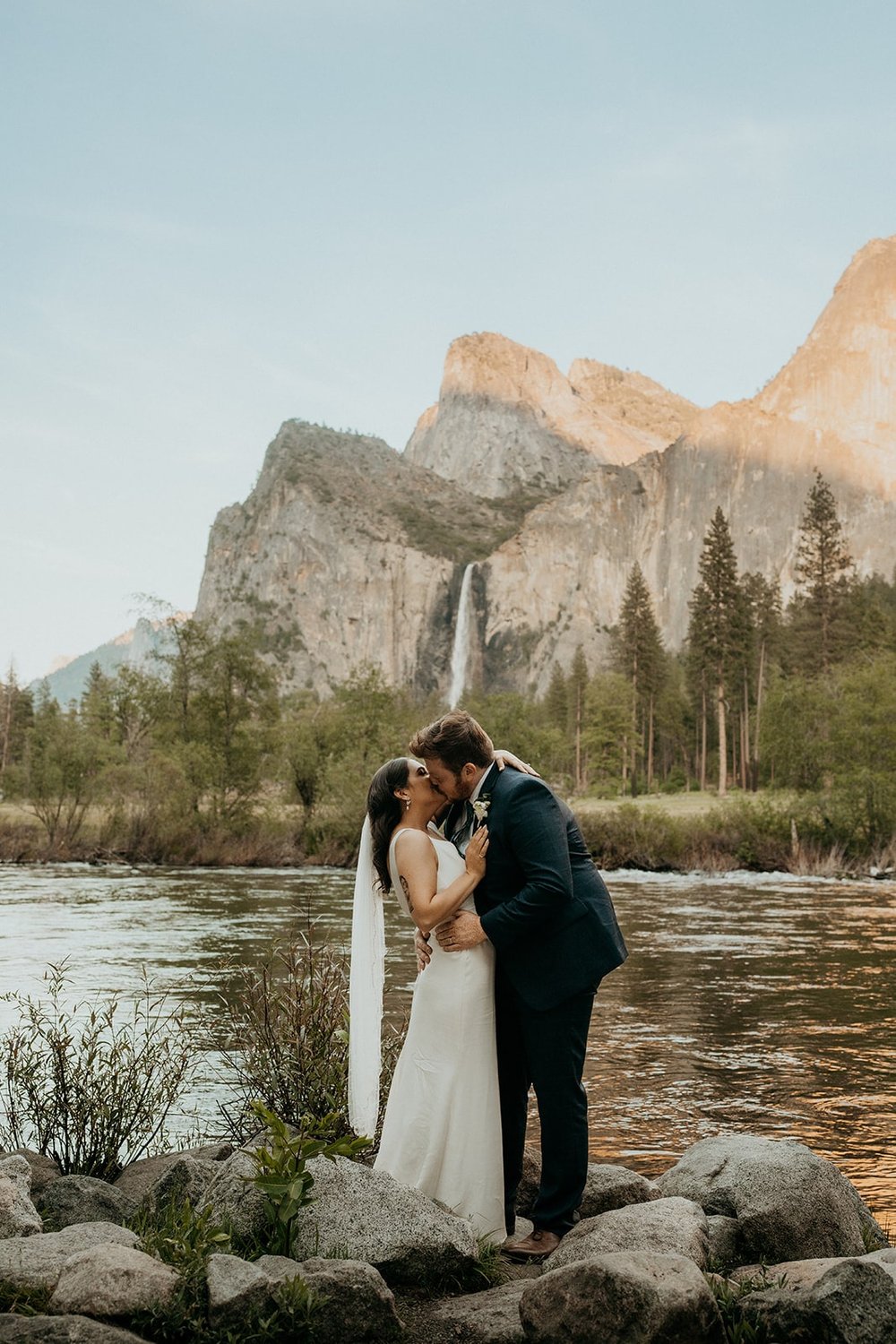 Bride and groom kiss in front of a lake during their Yosemite National Park elopement