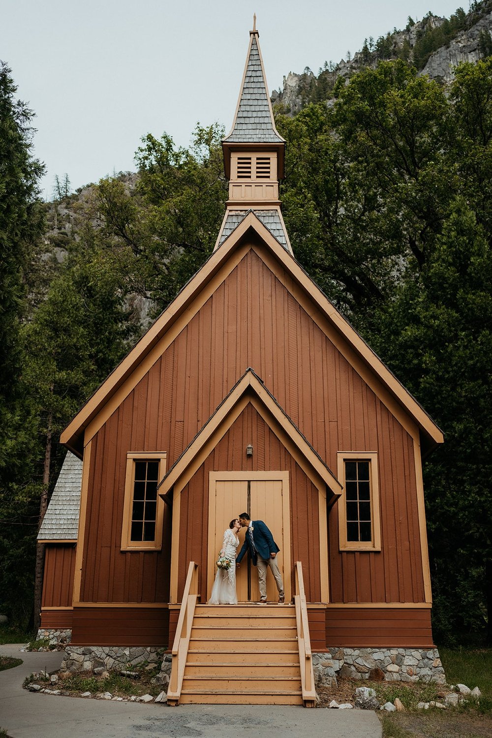 Bride and groom kiss in front of Yosemite chapel