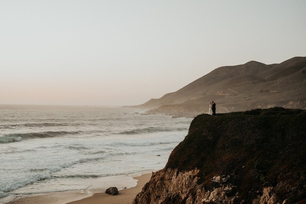 Bride and groom stand on a cliff during their Big Sur elopement photos