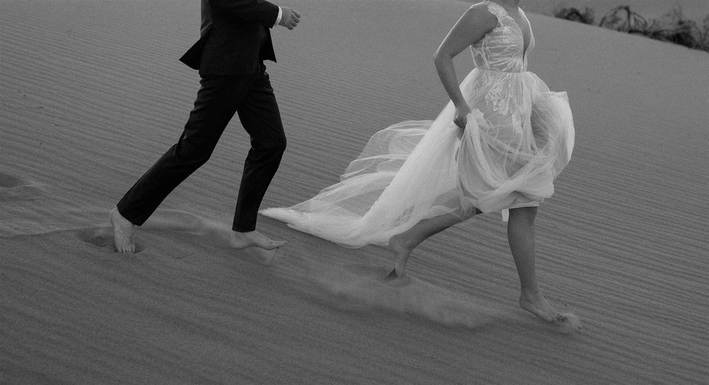 Bride and groom run across the sand dunes during their Death Valley elopement in California
