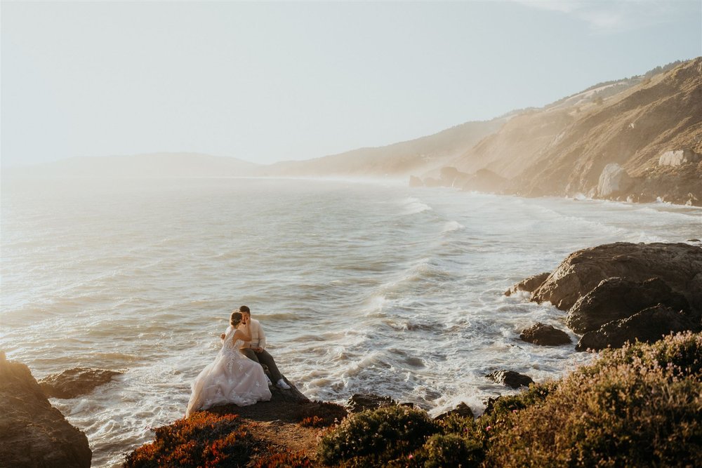 Bride and groom sit on the cliffs overlooking the ocean during their elopement in Marin Headlands, California