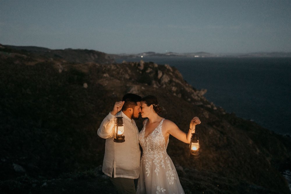 Bride and groom hold lanterns during blue hour elopement photos in Marin Headlands