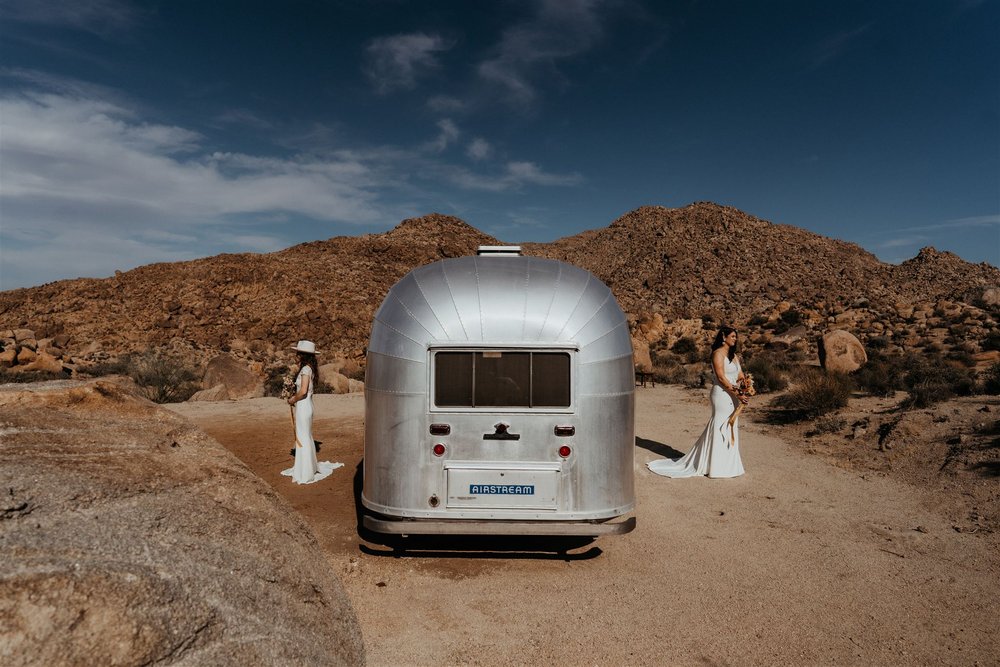 Two brides prepare for their first look next to an Airstream camper in Joshua Tree National Park