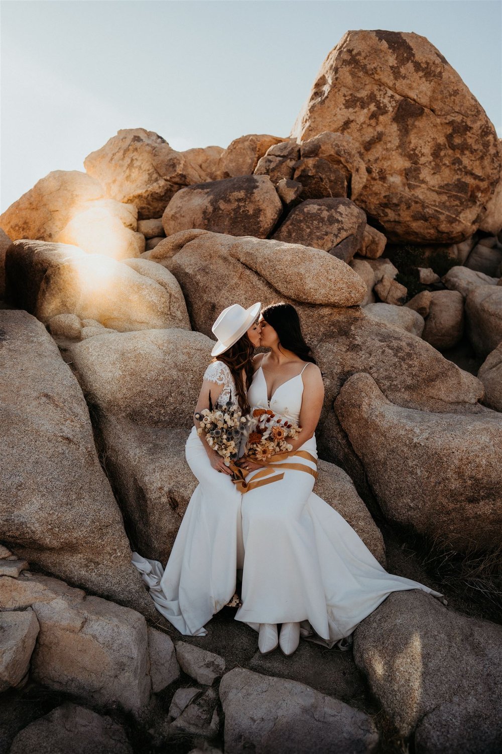 Two brides kiss on the rocks at their Joshua Tree elopement in California