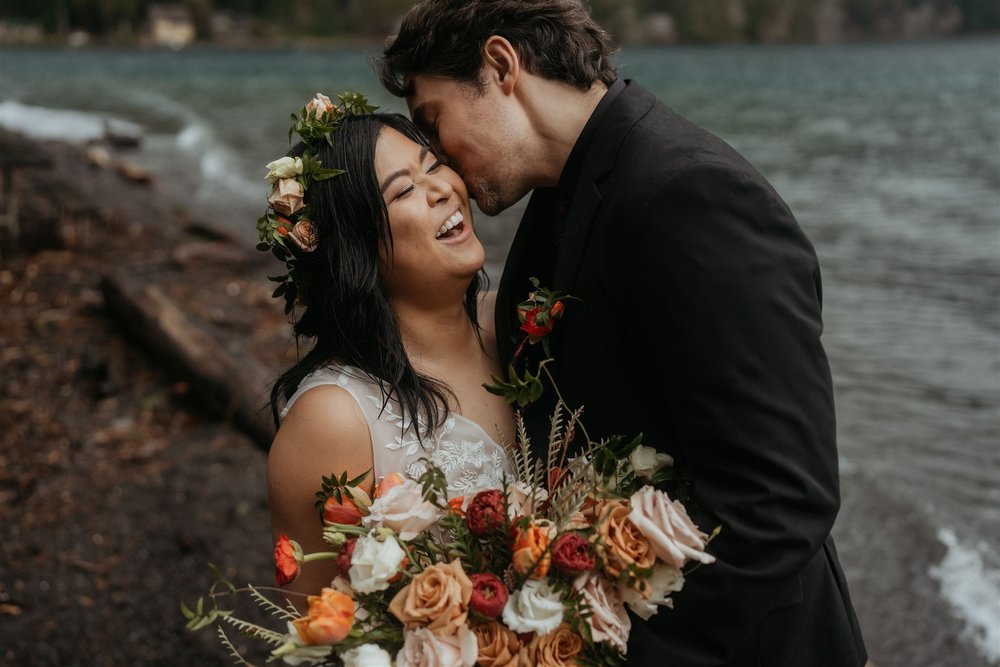 Bride laughs while groom kisses her on the cheek during their elopement in Olympic National Park